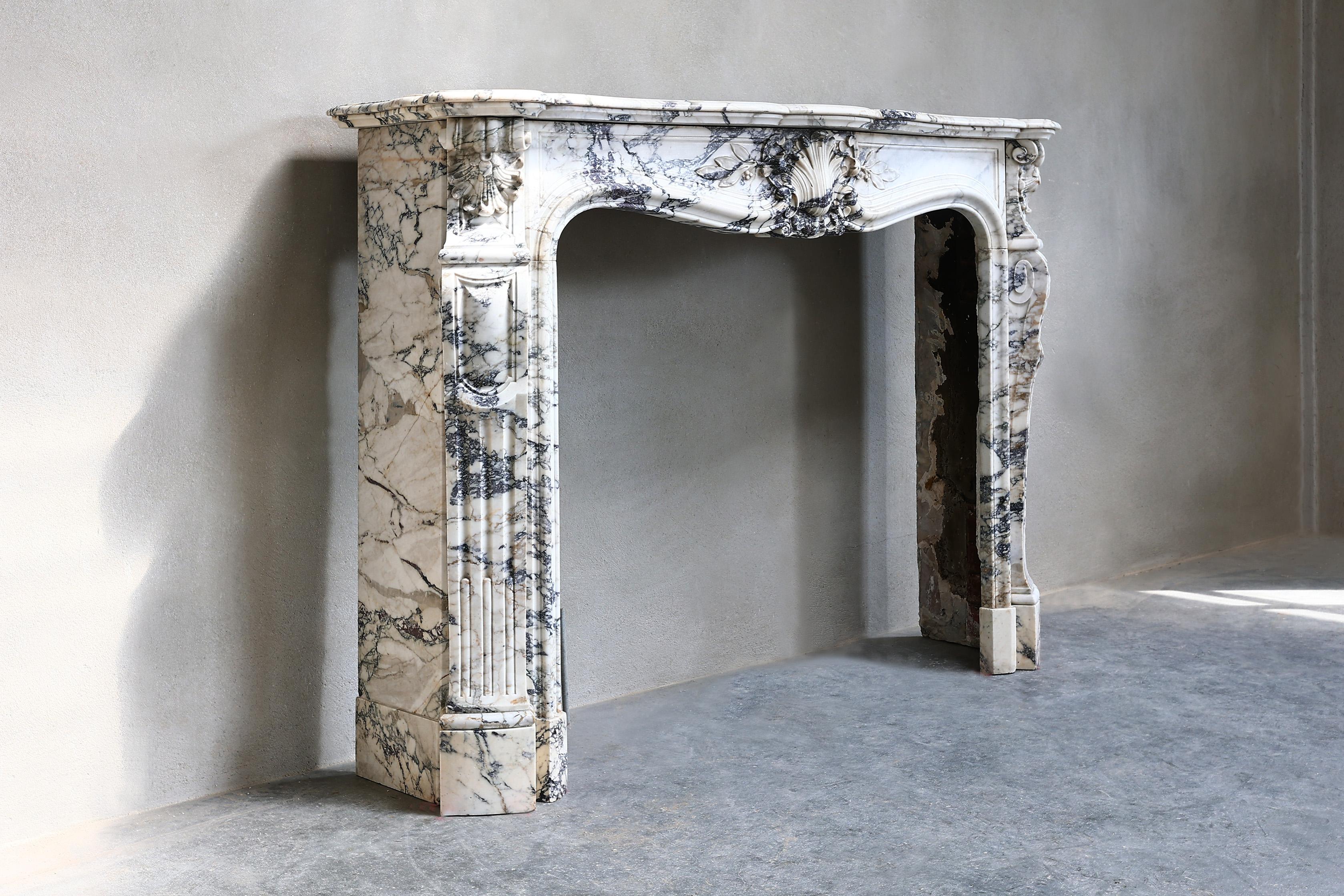 Beautiful unique and exclusive fireplace of Paonazzo marble from the 19th century! This antique French fireplace is in the style of Louis XV and has a scallop in the middle and on the sides of the front part. This beautiful type of marble with its