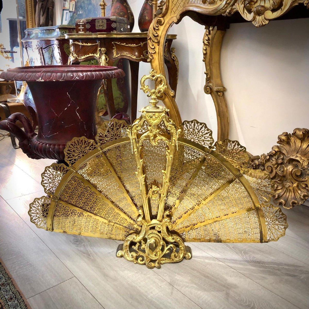 This exquisite fireplace screen is crafted in the shape of a peacock and features eight retractable elements. The bronze exhibits superb gilding, with minor signs of wear on the most exposed areas of this piece. It is in flawless working condition