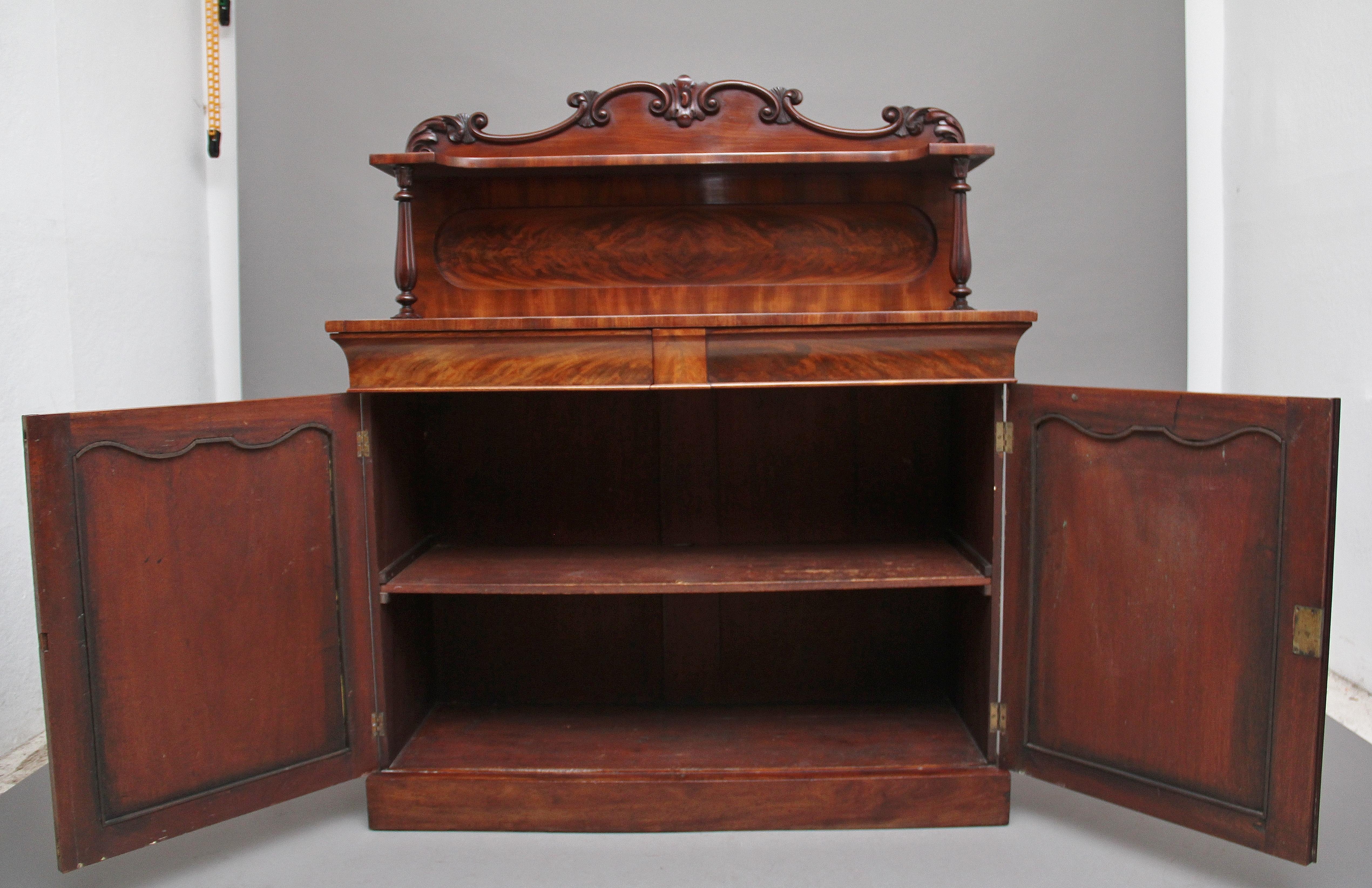 Chiffoniere in mogano a fiamma del XIX secolo, con frontone sagomato e modellato a volute intagliate sopra un ripiano sagomato con un pannello in mogano a fiamma sottostante, il ripiano sostenuto da colonne sagomate e intagliate, la base con due