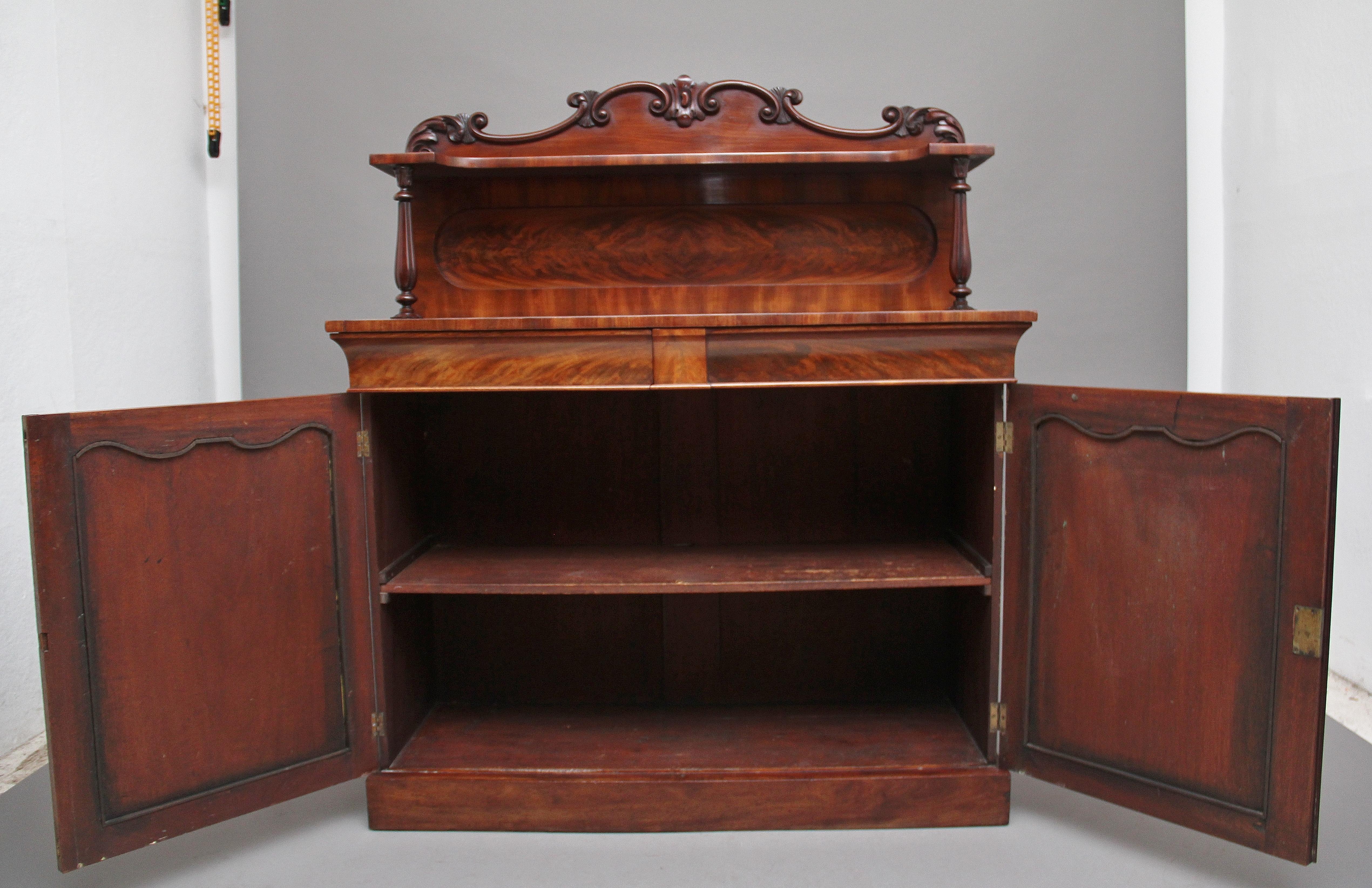 19th century flame mahogany chiffonier, having a shaped and moulded carved scrolled pediment above a shaped shelf with a flame mahogany panel below, the shelf supported with shaped and carved columns, the base having two mahogany lined frieze