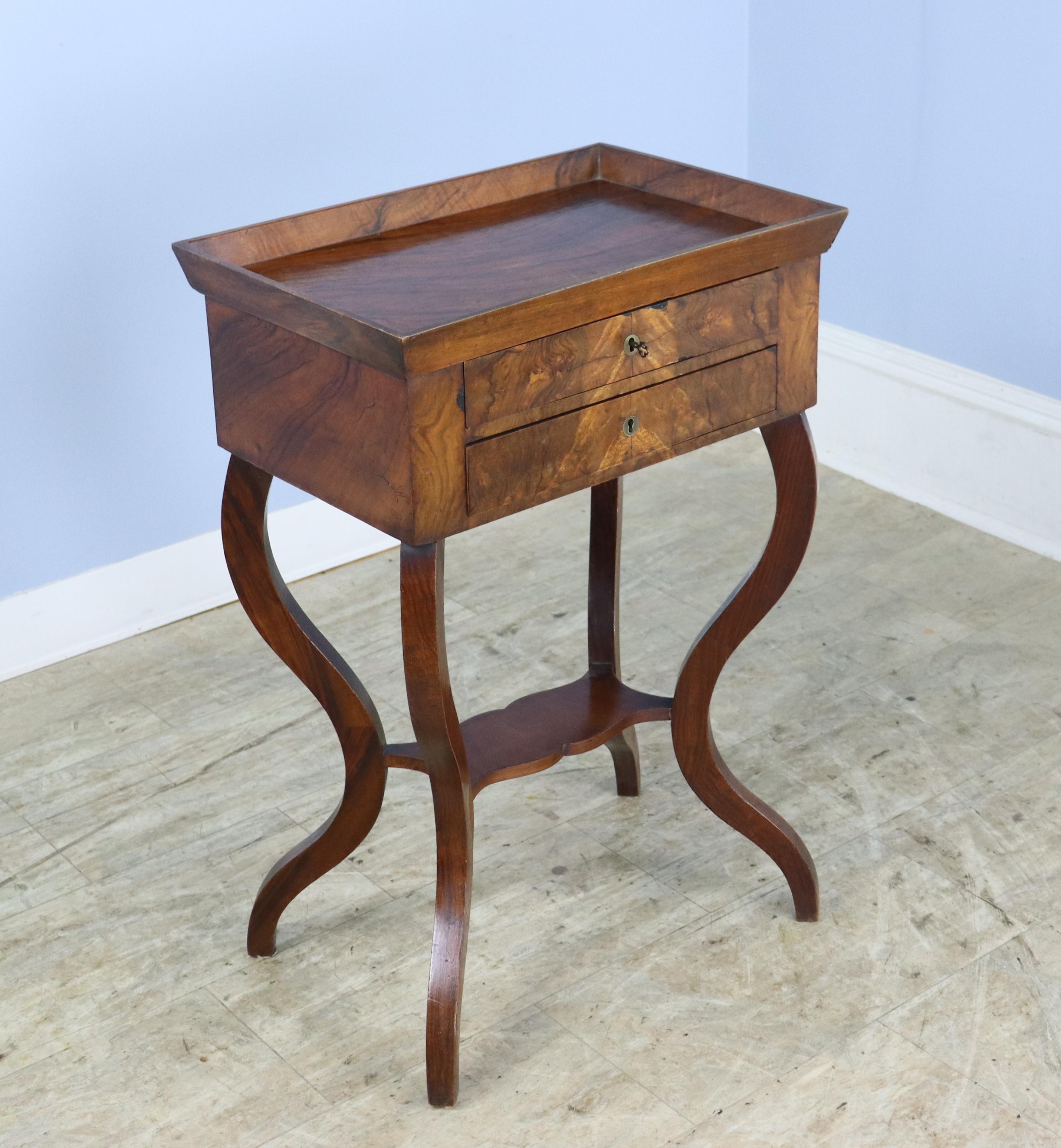 A dainty tray top side or occasional table in well grained flame mahogany.  High galleried top and articulated cabriole legs complete the look.  There is one small key for use as a drawer pull for either of the small front drawers.