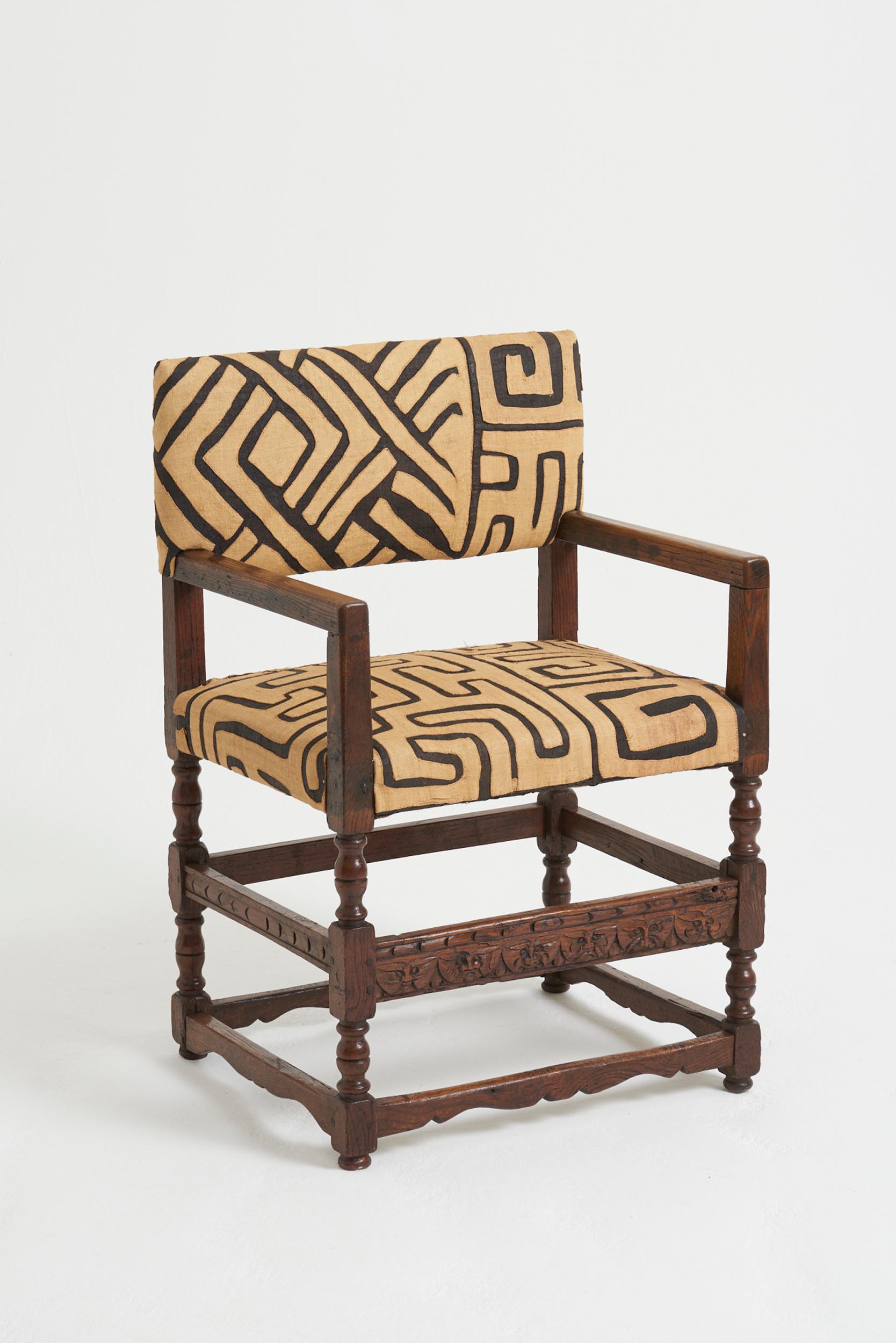 A Flemish oak armchair, with most unusual carved Green Man motifs on the stretcher. Upholstered in Kuba cloth from the Congo. 
Holland, 19th Century
