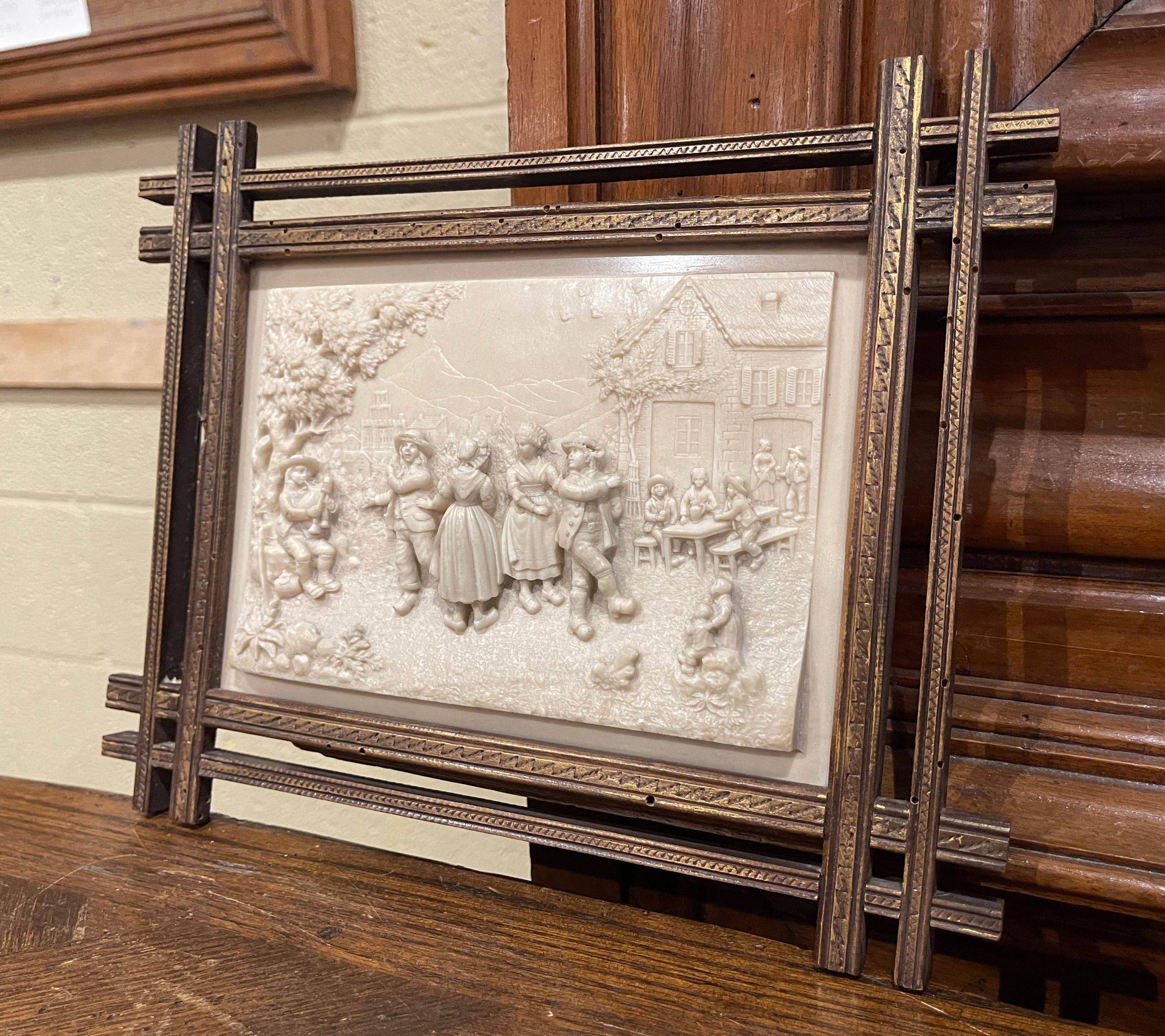Decorate a dining room or a living room with this signed C.F. Baker antique sculpted alabaster plaque. Created in Belgium, circa 1890 and set in a carved frame with gilt accents, the artwork depicts a festive scene in the manner of David Teniers,