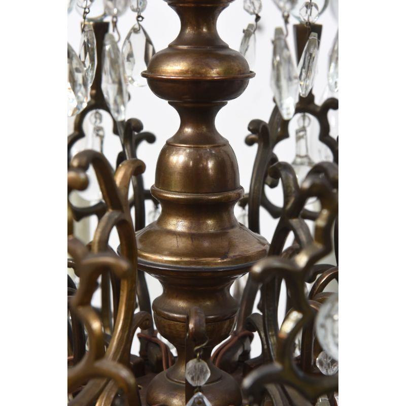 An unusual chandelier with characteristic Flemish brass casting and crystals. A single tier of candles topped with two tiers of brass arms topped with crystal balls to catch the light. Arms feature an unusual keyhole design with crystal hanging