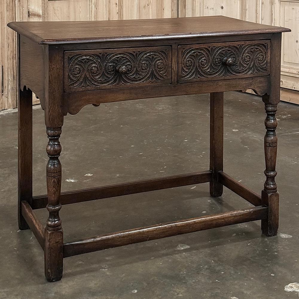 Console ~ table d'appoint flamande du 19e siècle est un modèle simple rendu attachant par le motif stylisé de coquilles et de guirlandes sur les façades des tiroirs, chacun d'eux étant équipé d'un bouton en bois tourné.  Un plateau en planches