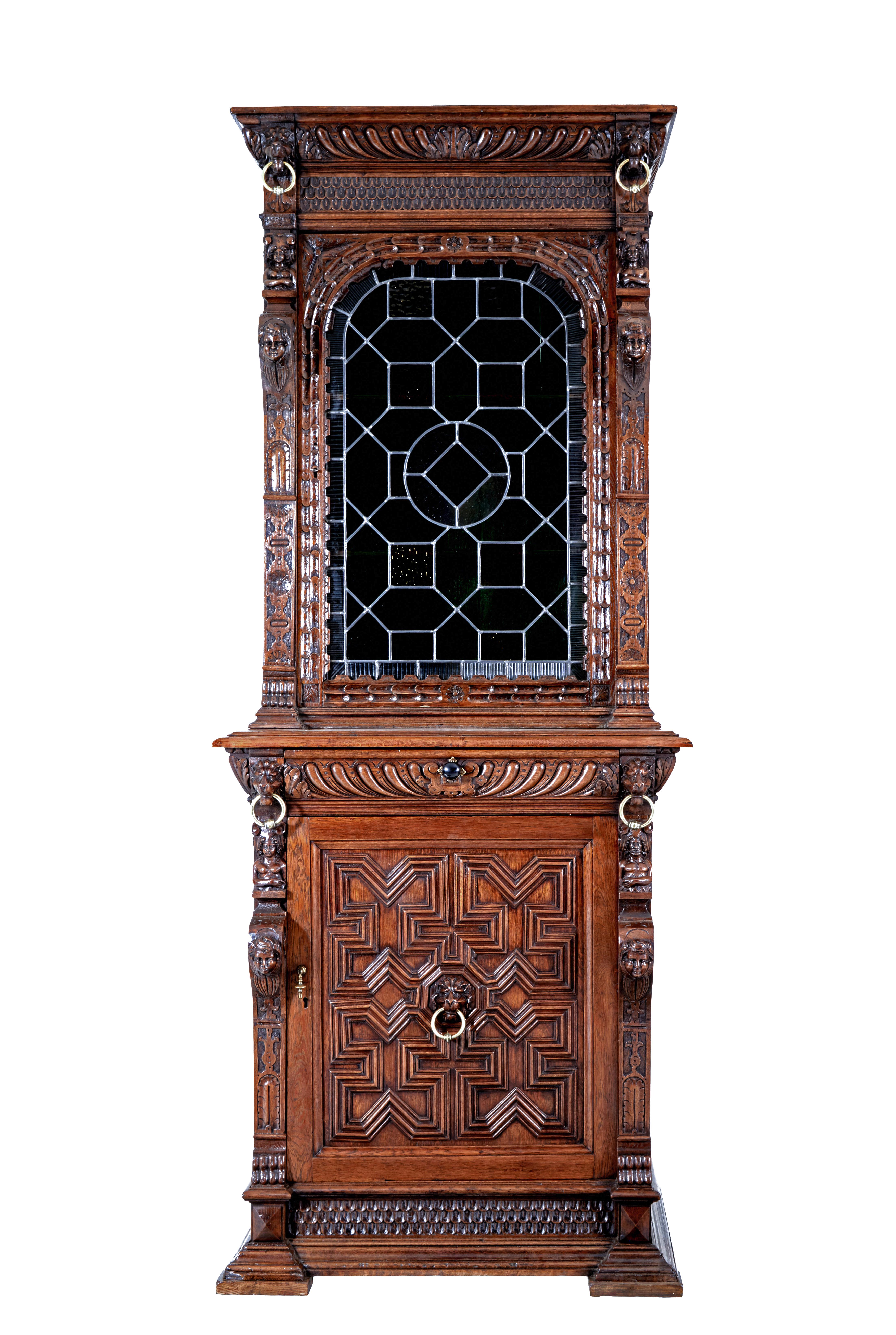 19th century flemish oak and stain glass cabinet circa 1890.

Narrow flemish cabinet comprising of 2 sections, which rarely comes with its original stained glass panel in the top section.  Profusely carved with lion heads and brass ring details. 
