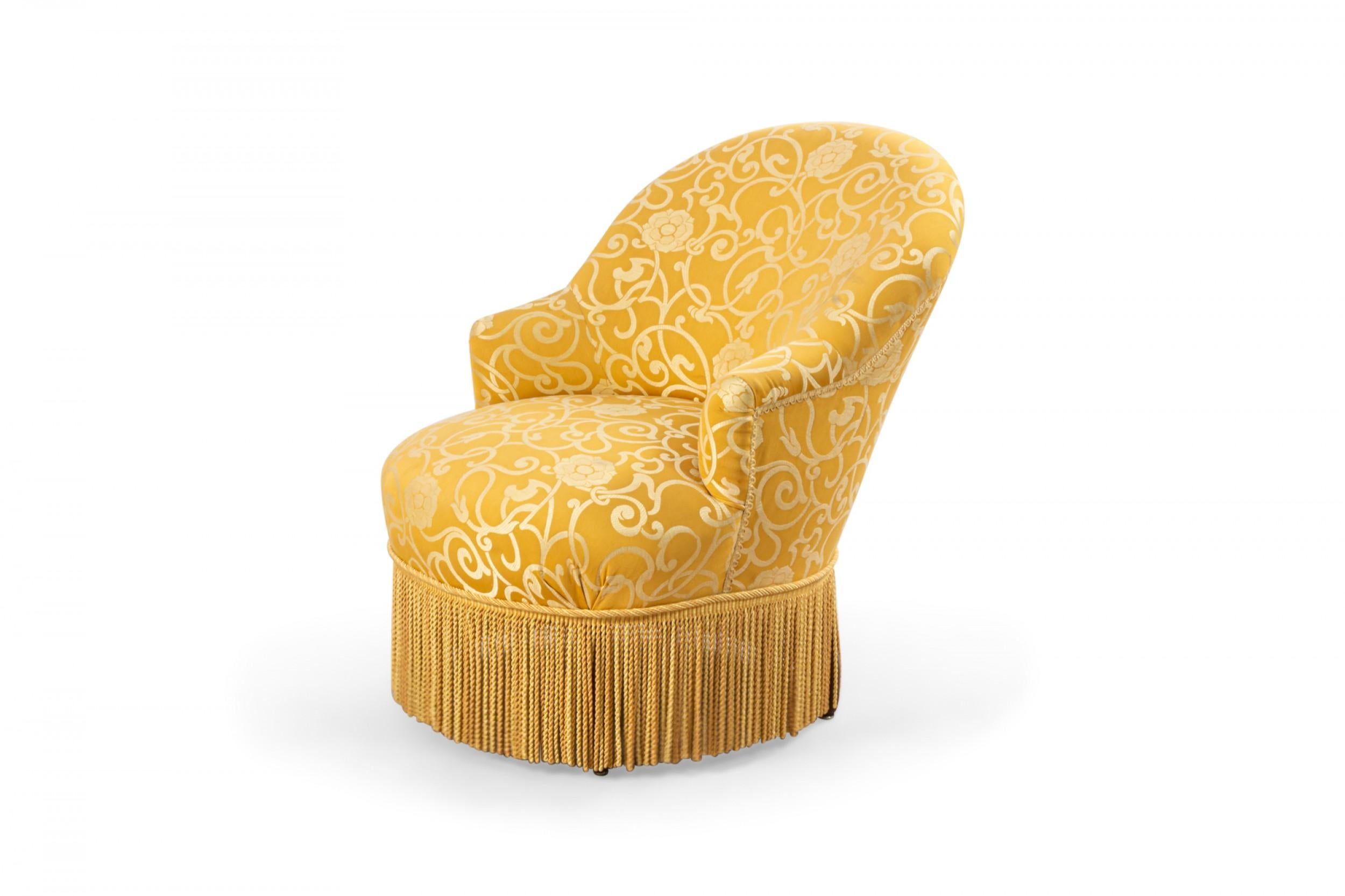 English Victorian Style 19th century boudoir chair in gold patterned upholstery with fringe along the bottom edge
