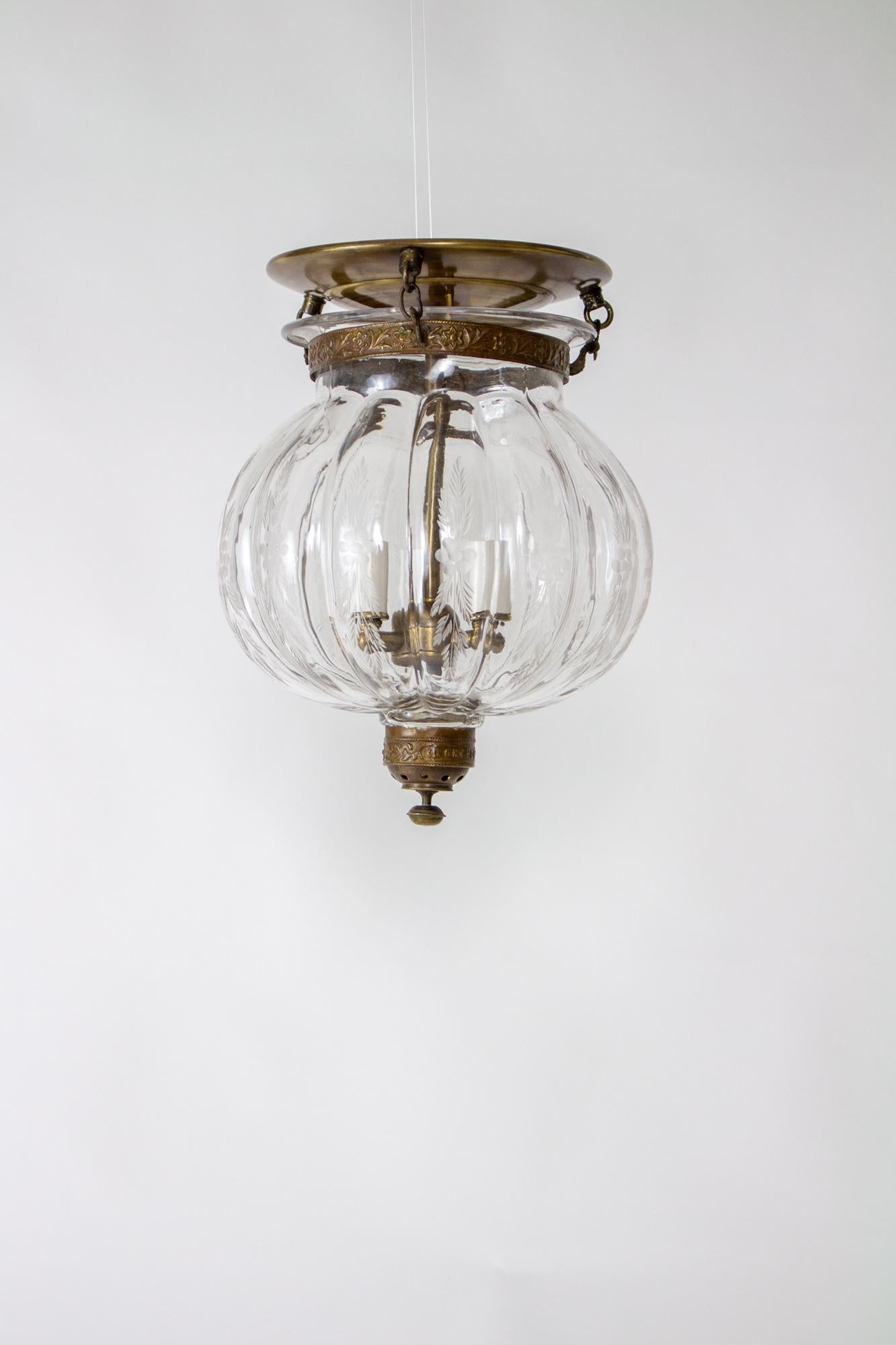 Bell jar lanterns first reached popularity in colonial India and due to their lingering popularity, production has continued to the present. Made from delicately blown clear glass with an engraved wheat pattern. The Glass is suspended by three