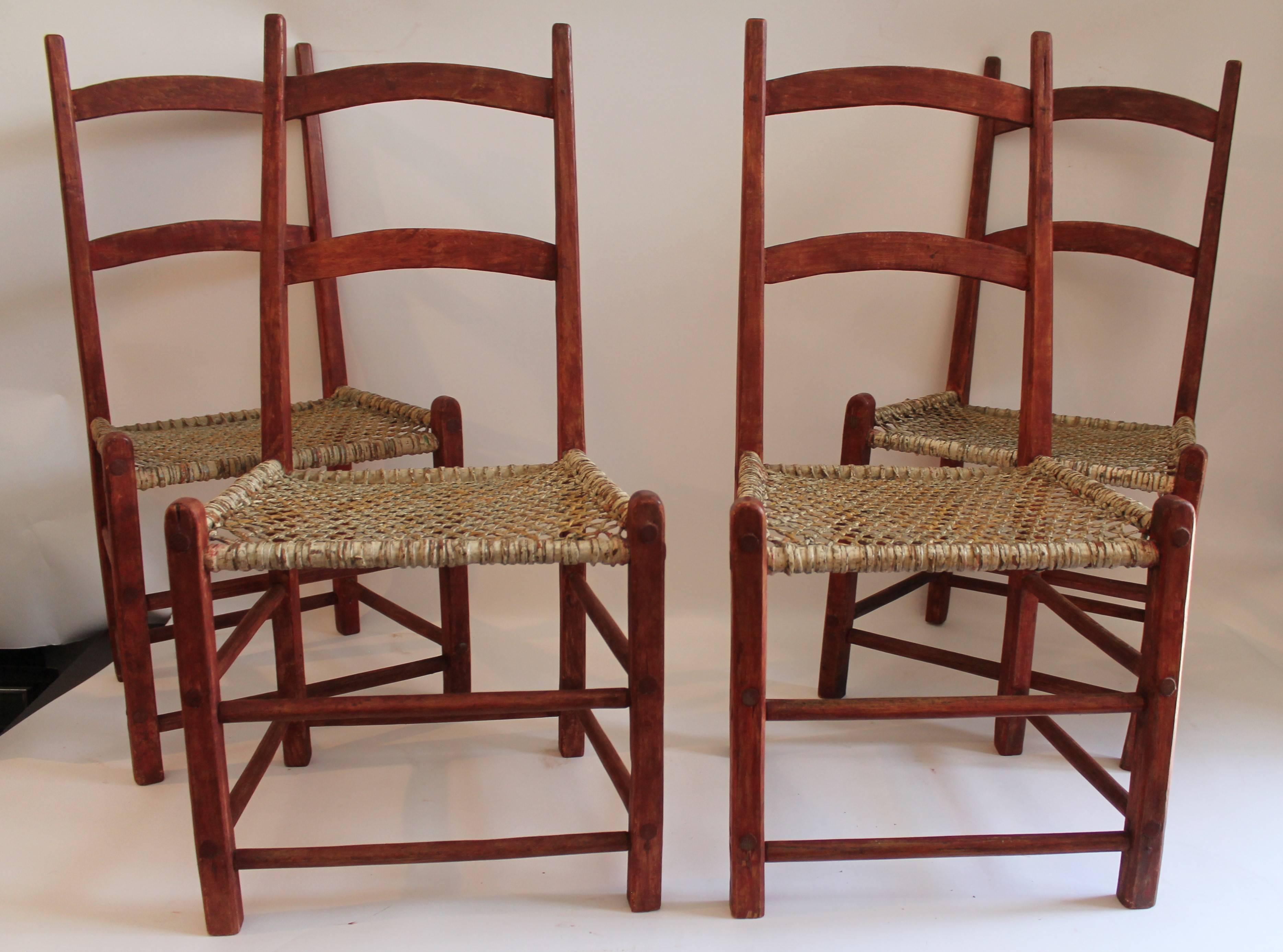 These folky red painted ladder back chairs from Canada are in good sturdy condition and they retain the original white painted rawhide seats. Seat height is 15 inches. They have a bittersweet/redish surface. Set of four are all in good condition.