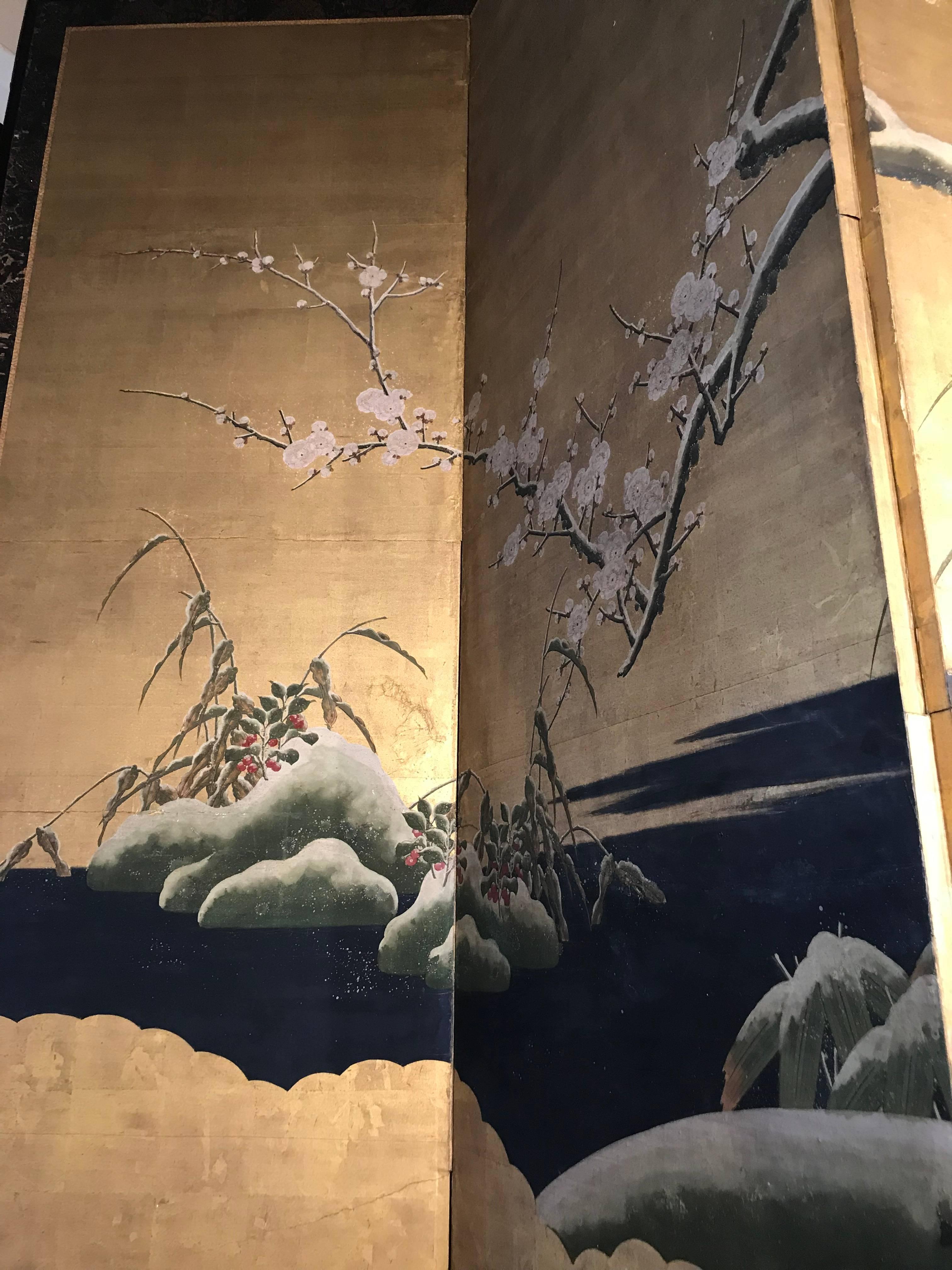 A very well painted four fold Kano School, Chinese influenced, Byobu of a late winter snow with red berries peeking through the snow. A pair of Mandarin ducks, a family symbol, are on a rock formation under a flowering prunus which was considered