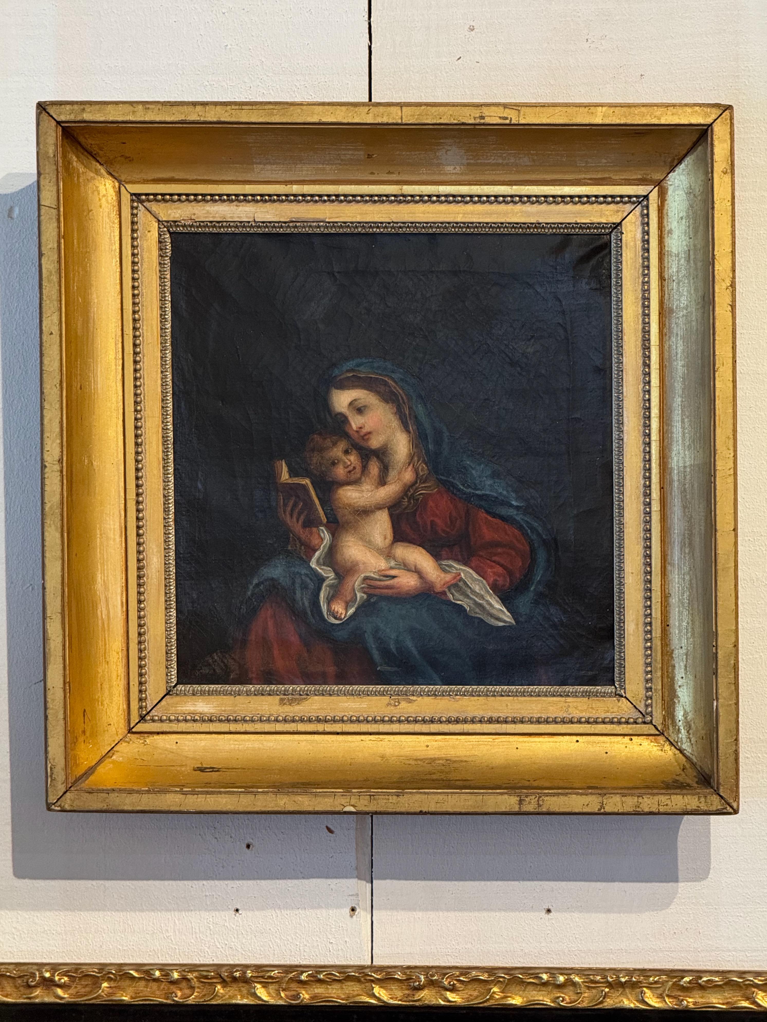 Gemälde aus dem 19. Jahrhundert in Öl auf Leinwand, das die Madonna mit Kind zeigt, wie sie mit einem aufgeschlagenen Buch in einem Moment stiller Intimität sitzt. Das Werk befindet sich in einem breiten Rahmen aus Goldholz mit Perlenverzierung und