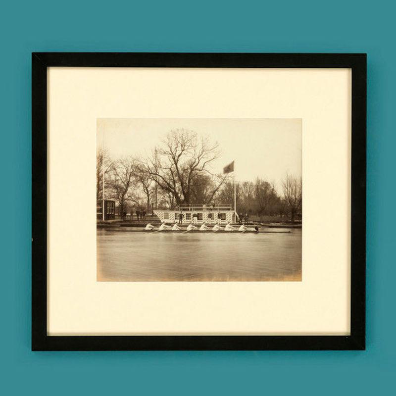 Framed albumen print of rowers passing the committee barge.
 