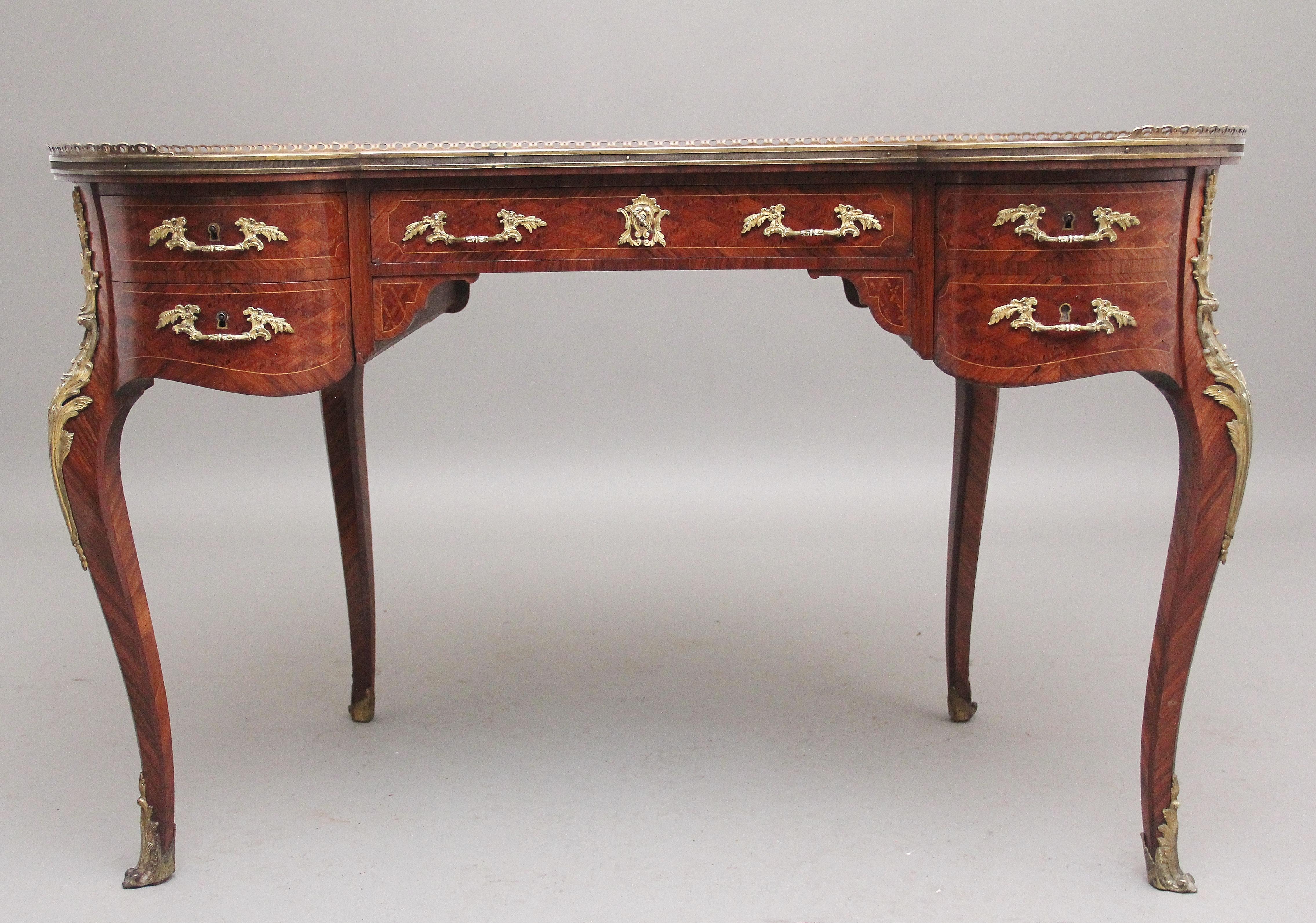 19th century freestanding French parquetry and Kingwood kidney desk, the kidney shaped top having a green leather writing surface decorated with blind and gilt tooling, a Kingwood border and a decorative brass gallery, with a brass moulding running