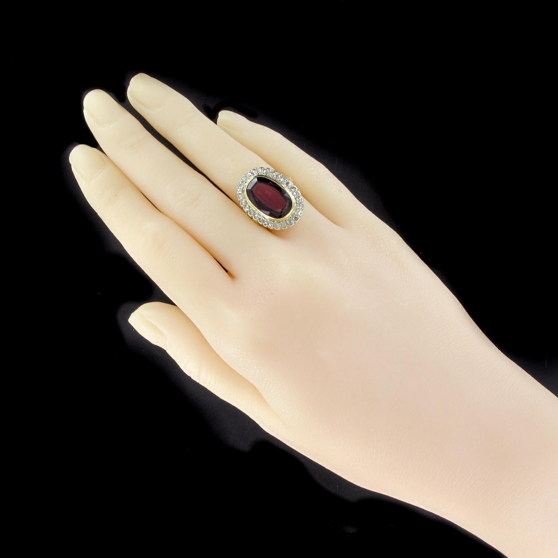 Ring in 18 karats yellow gold, eagle's head hallmark.
This voluminous antique ring is set in the center of an oval garnet in an entourage of rose-cut diamonds. The start of the ring is formed on either side of a lily flower.
Total weight of garnet: