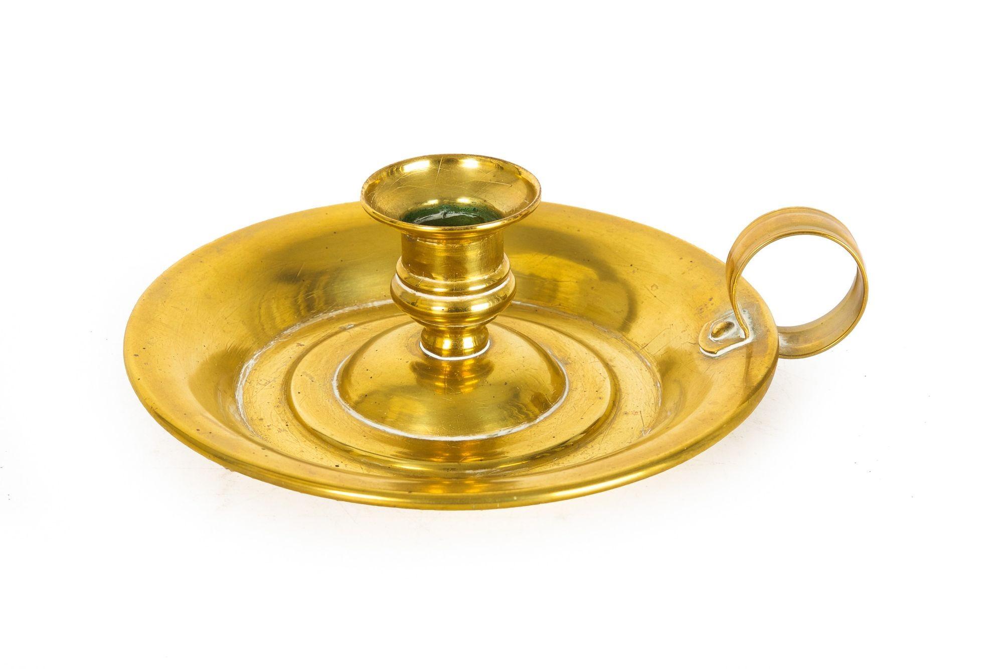 A simple and austere brass single candlestick holder, the lower 