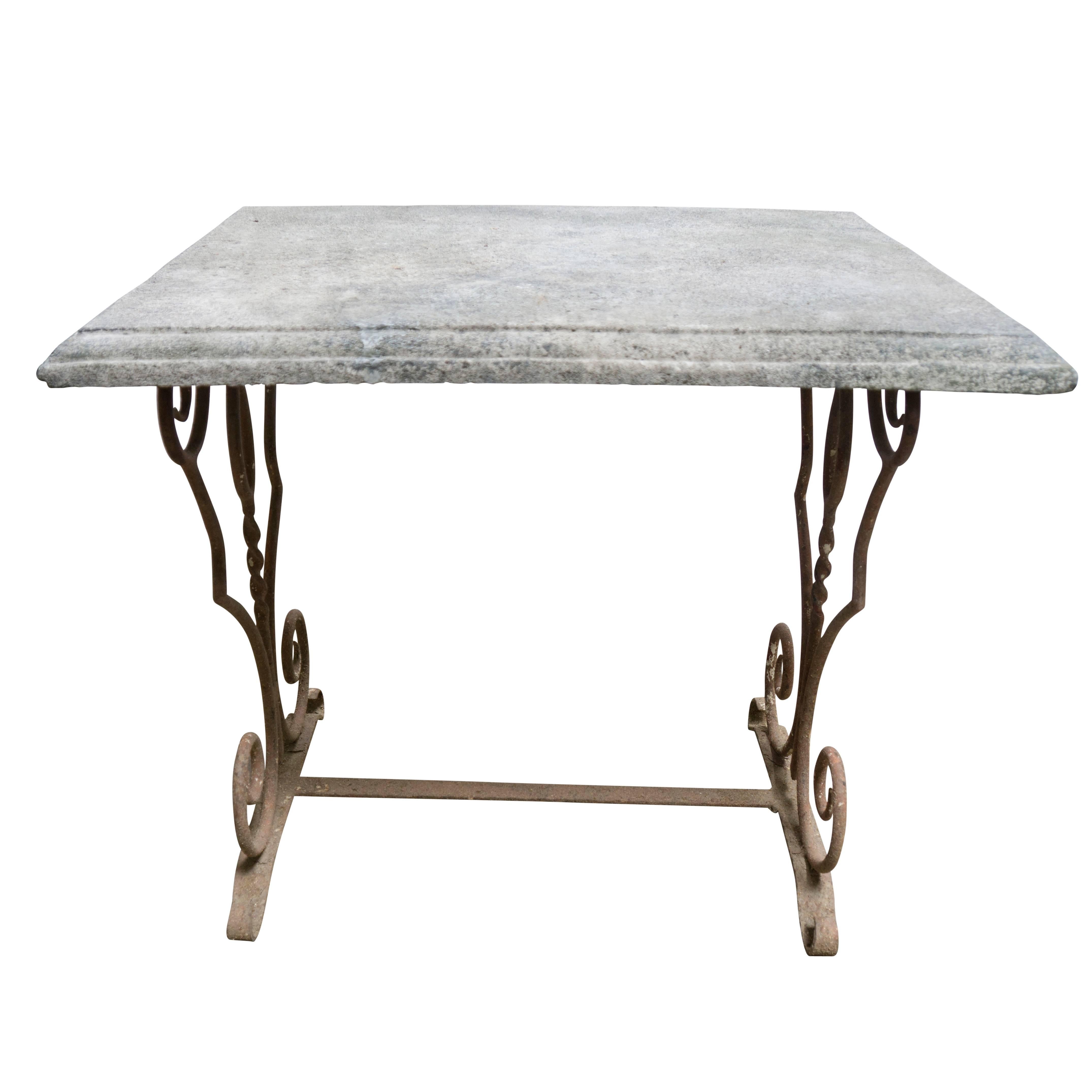 An end table size antique that is better used out in the open. The limestone top is porous, contains a nice blend of grey minerals, and has been handcrafted with a three step curved edge. The iron base is decorated in a simple four spiral fashion