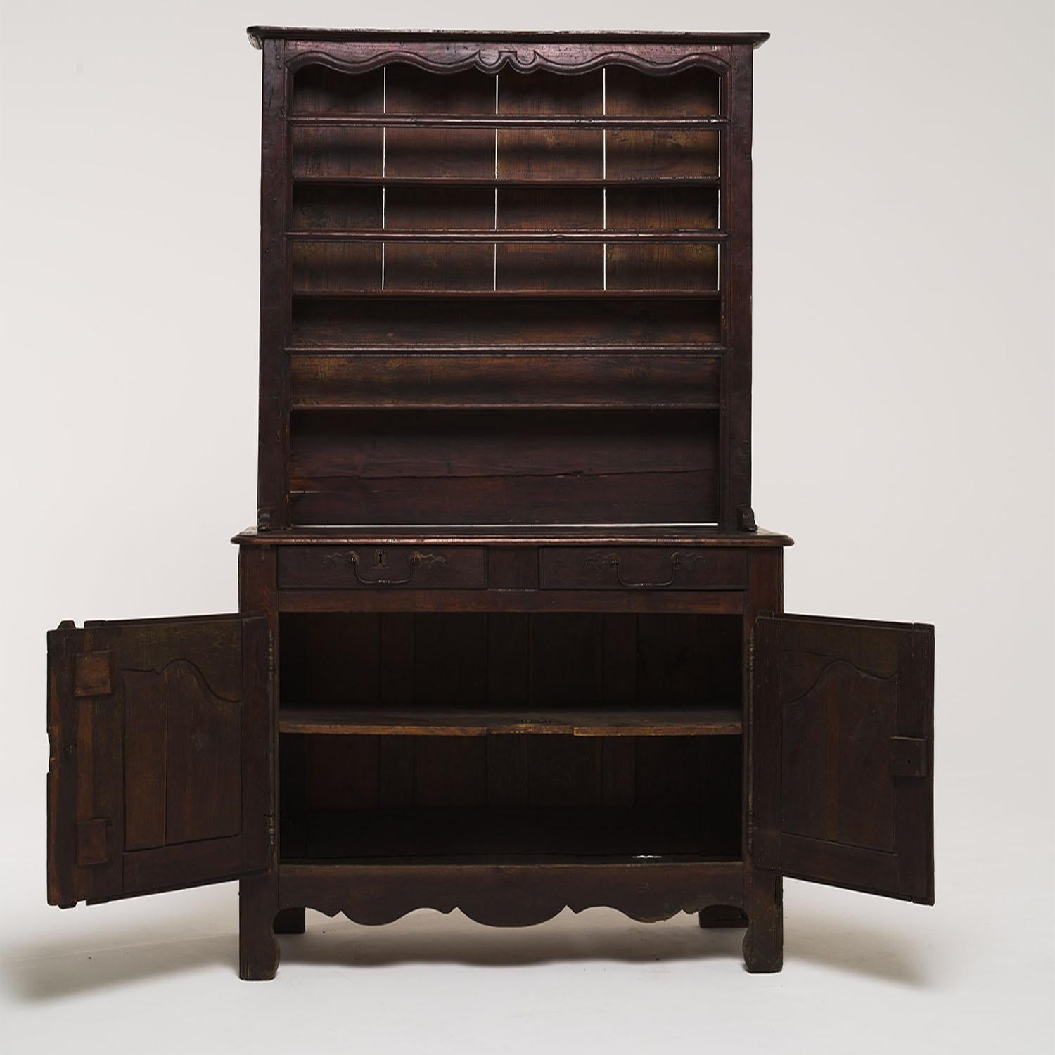 An antique French Vaisselier made of hand crafted Oakwood, in good condition. The word Vaisselier refers to a piece of furniture for storing and displaying dishes. The detailed buffet is composed with a shelf cabinet which is resting on the lower