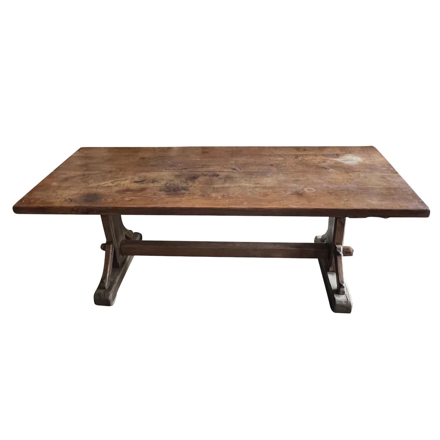 A 19th century wooden trestle table made of hand crafted Walnut, in good condition. The massive plank top rests on carved legs and is joined by a stretcher. The antique French table has beautifully weathered to a subtle patina revealing glimpses of