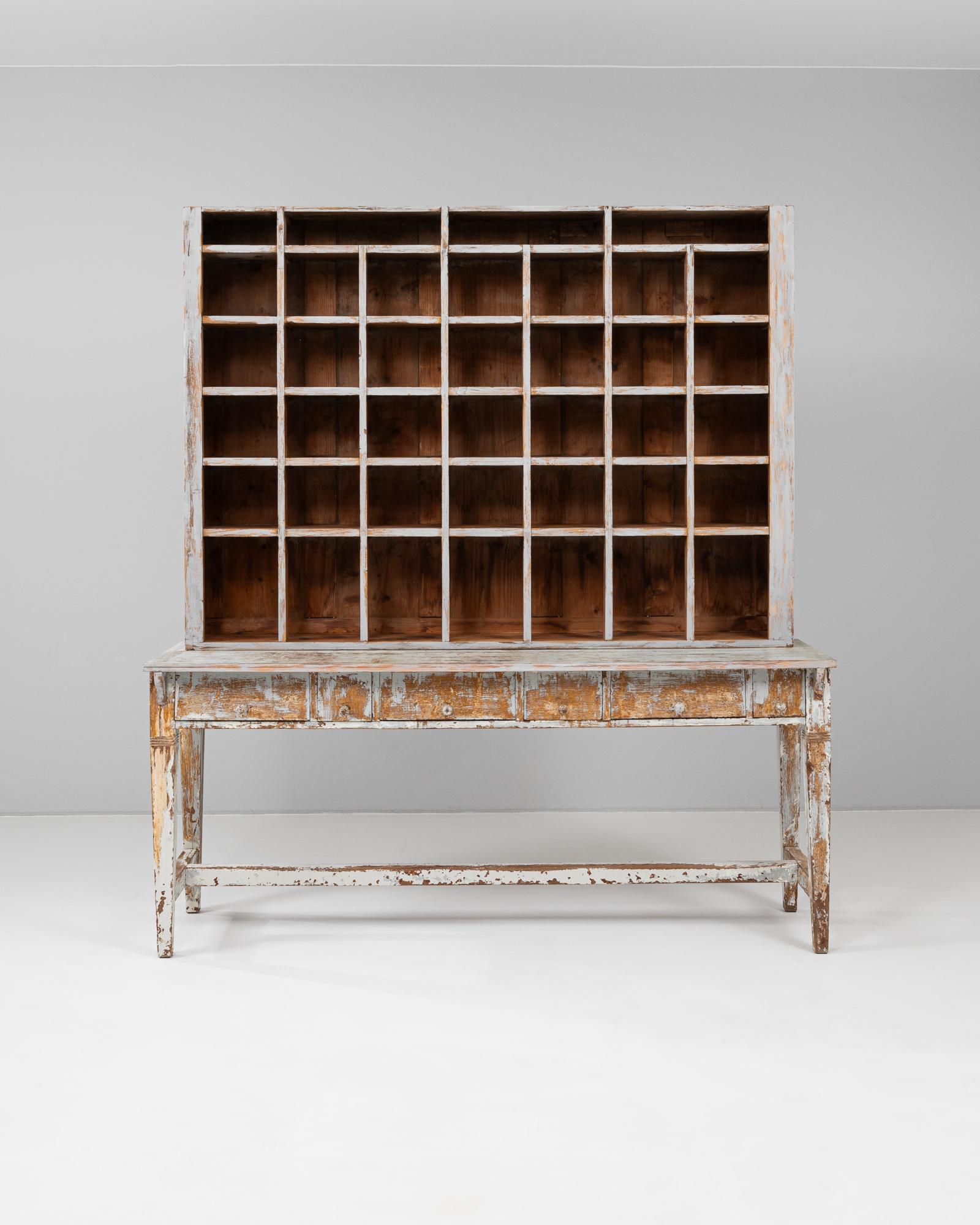 This 19th Century French apothecary cabinet is a remarkable example of utilitarian design with enduring character. Crafted from solid wood and featuring its original timeworn paint, the cabinet includes a bank of 40 cubby compartments above a long