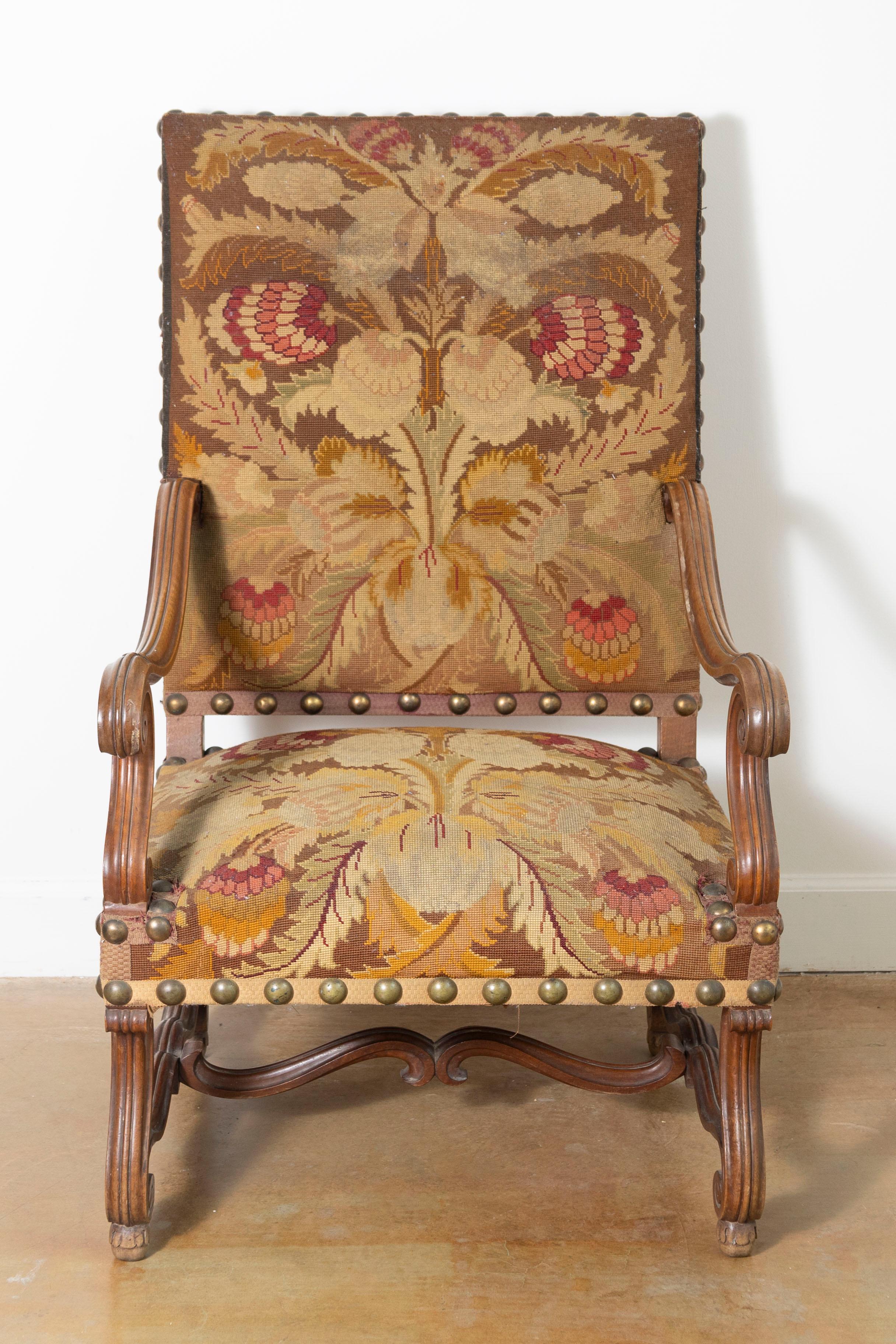 This 19th-century French armchair showcases the elegance and craftsmanship of its era, making it a timeless statement piece. The chair features a solid wood frame, walnut, with beautifully carved details along the arms, legs, and stretcher. Its