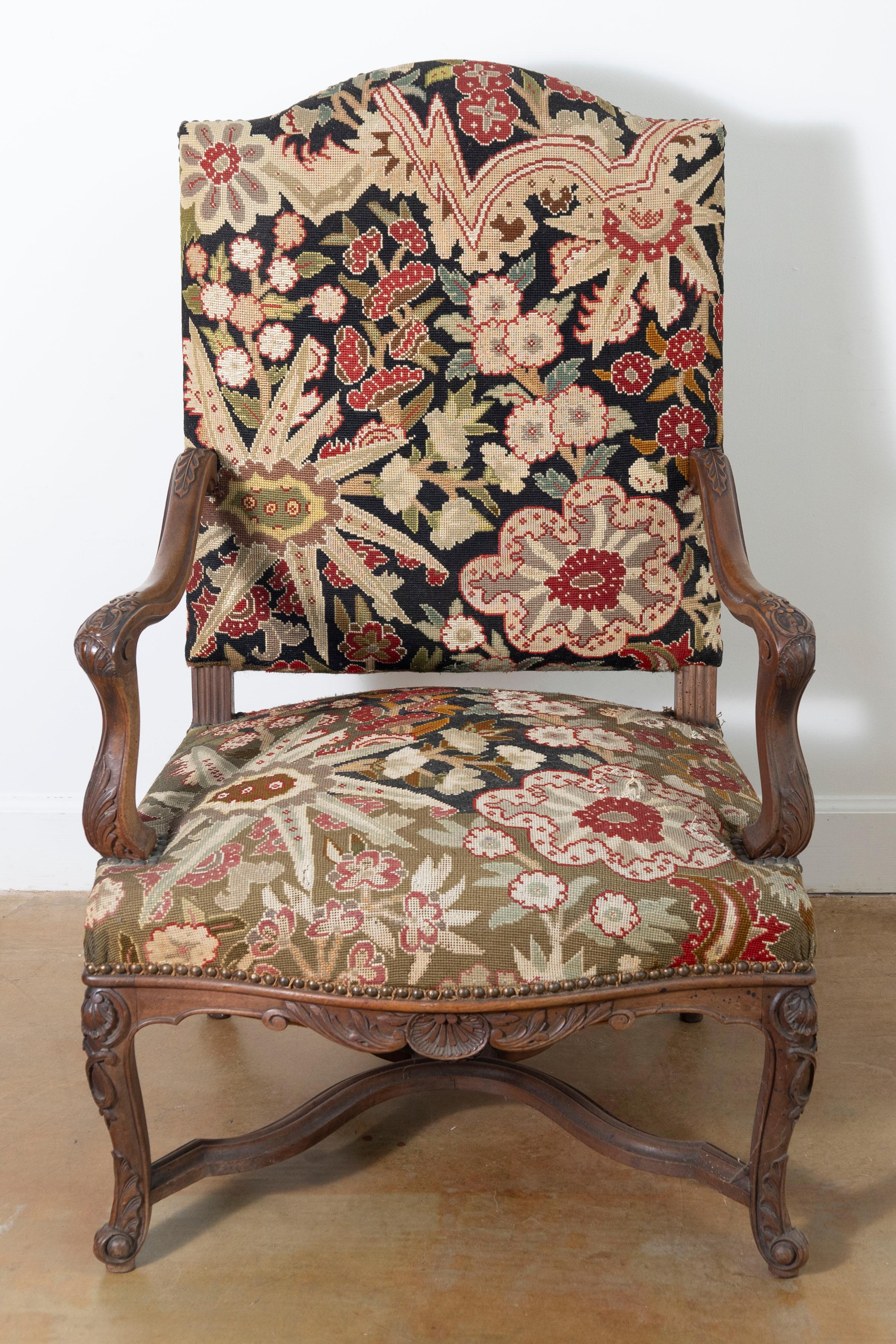 This 19th-century French armchair exemplifies refined craftsmanship and timeless design, showcasing the elegance of Louis XV or Rococo-inspired styles. The solid wood frame, likely walnut, is intricately carved with floral motifs, scrolling details,