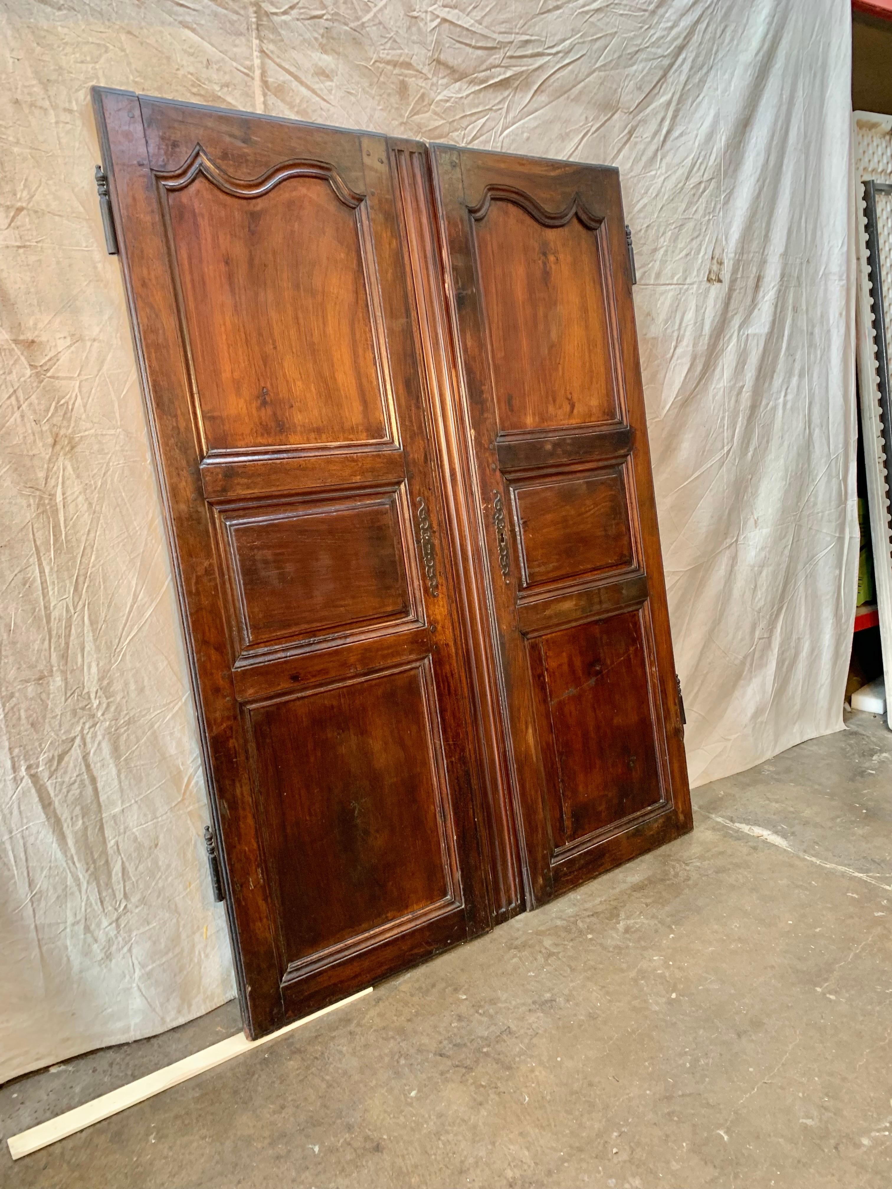 Found in the South of France, this pair of 19th Century French Armoire Doors once graced a beautiful armoire that was made in the 1800's. Hand crafted from walnut, each door displays three panels, the original escutcheon plate and partial hinge.