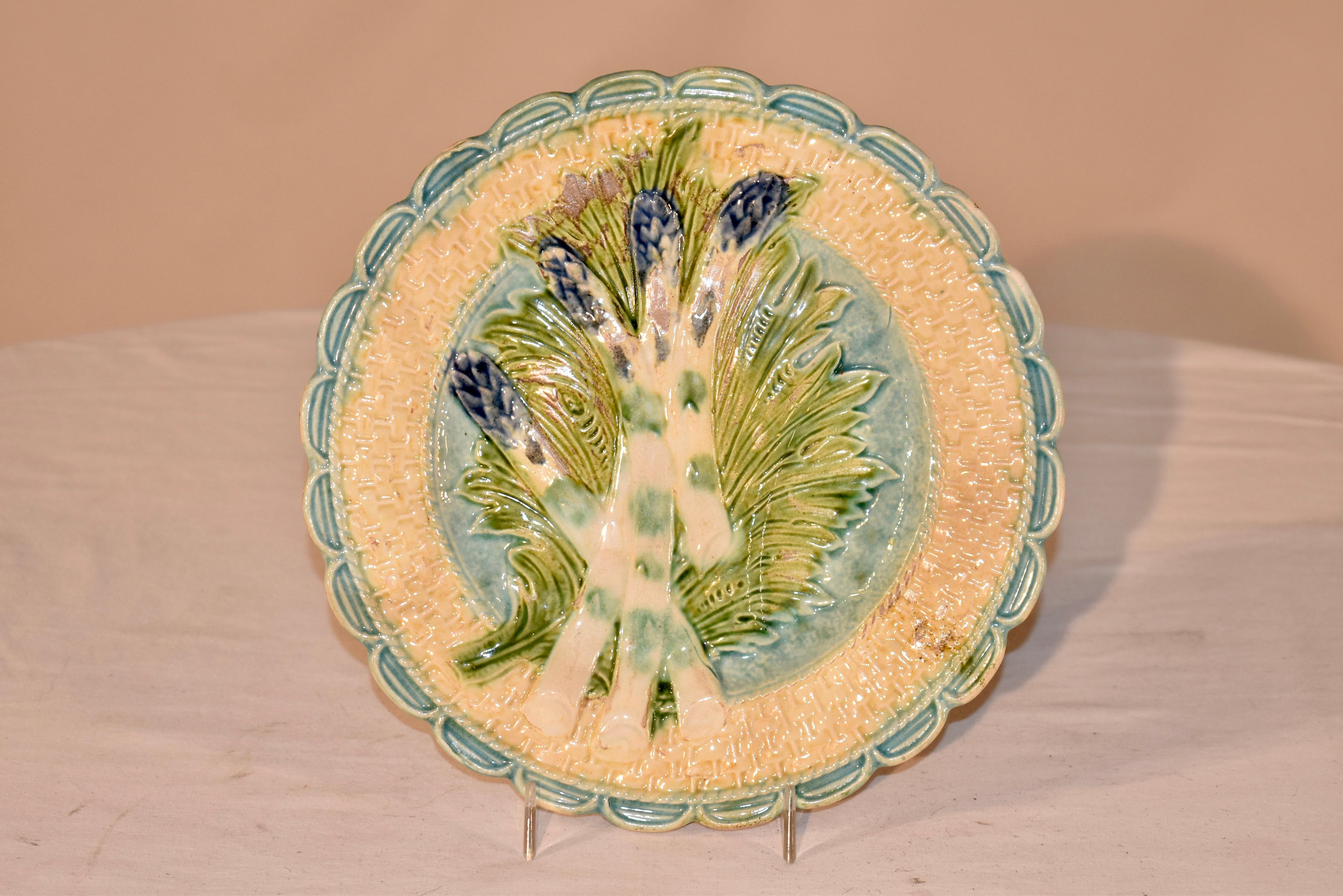 Assiette à asperges en majolique française de la fin du XIXe siècle, fabriquée par Salins, vers 1880.  L'asperge est posée sur un lit de feuilles et semble être dans un panier avec une bordure festonnée.  Belle couleur et belle taille.