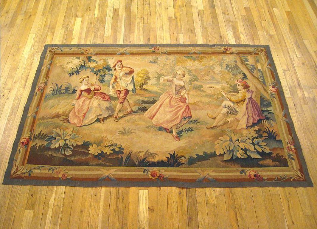 A French Aubusson romantic rustic tapestry from the 19th century, depicting a playful courtship scene in which two pairs of noble’s repose in a verdant woodlands setting, with one couple dancing at center, a noblewoman seated at left, and a