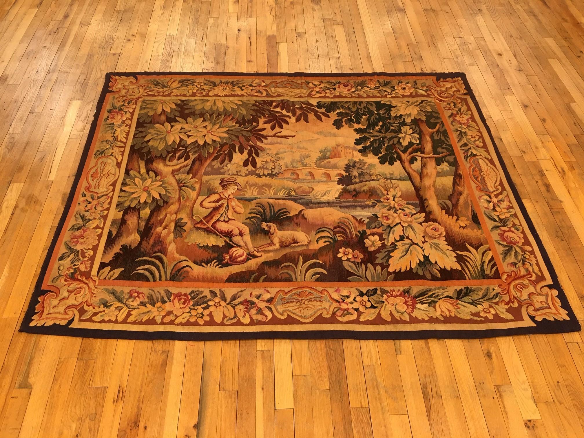 A French Aubusson rustic pastoral tapestry from the 19th century, centrally woven, depicting a young swain traveling with his faithful dog in an idyllic wooded area characterized by placidity and ethereal beauty. With flowering and acanthus plants