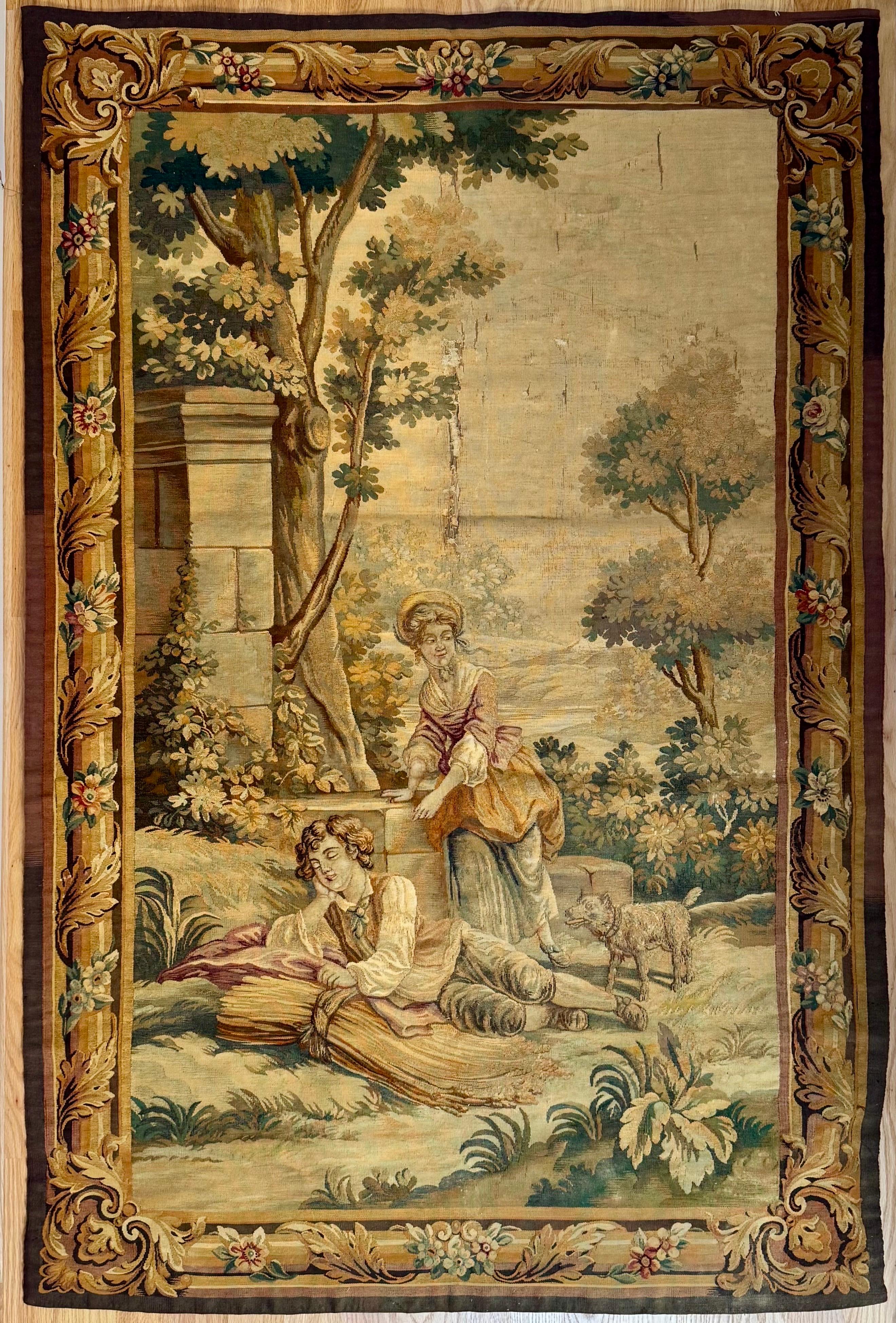 Handwoven in Aubusson, France in the 19th Century, this lovely Tapestry features a pair of lovers in a classic Rococo vinyet and has its original fruit and floral border. It measures 6.3 x 4.3 ft. The composition is embellished with large trees. The