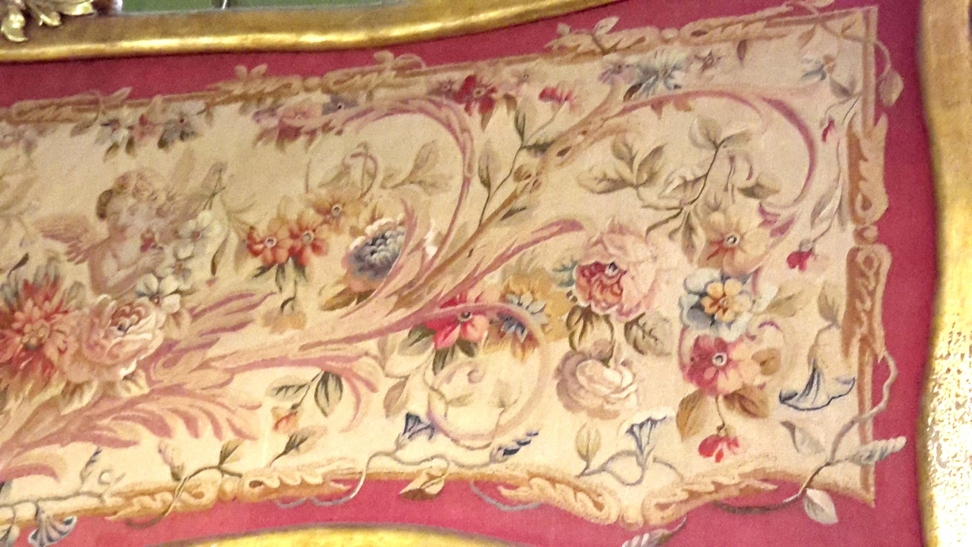 Louis XVI style handmade Aubusson tapestry panel in giltwood frame. Depicting garlands, flowers and cherubs. The colors are beautifully oxidized into a rich antique pinkish red and beige. Approximately 80 x 25 inches.