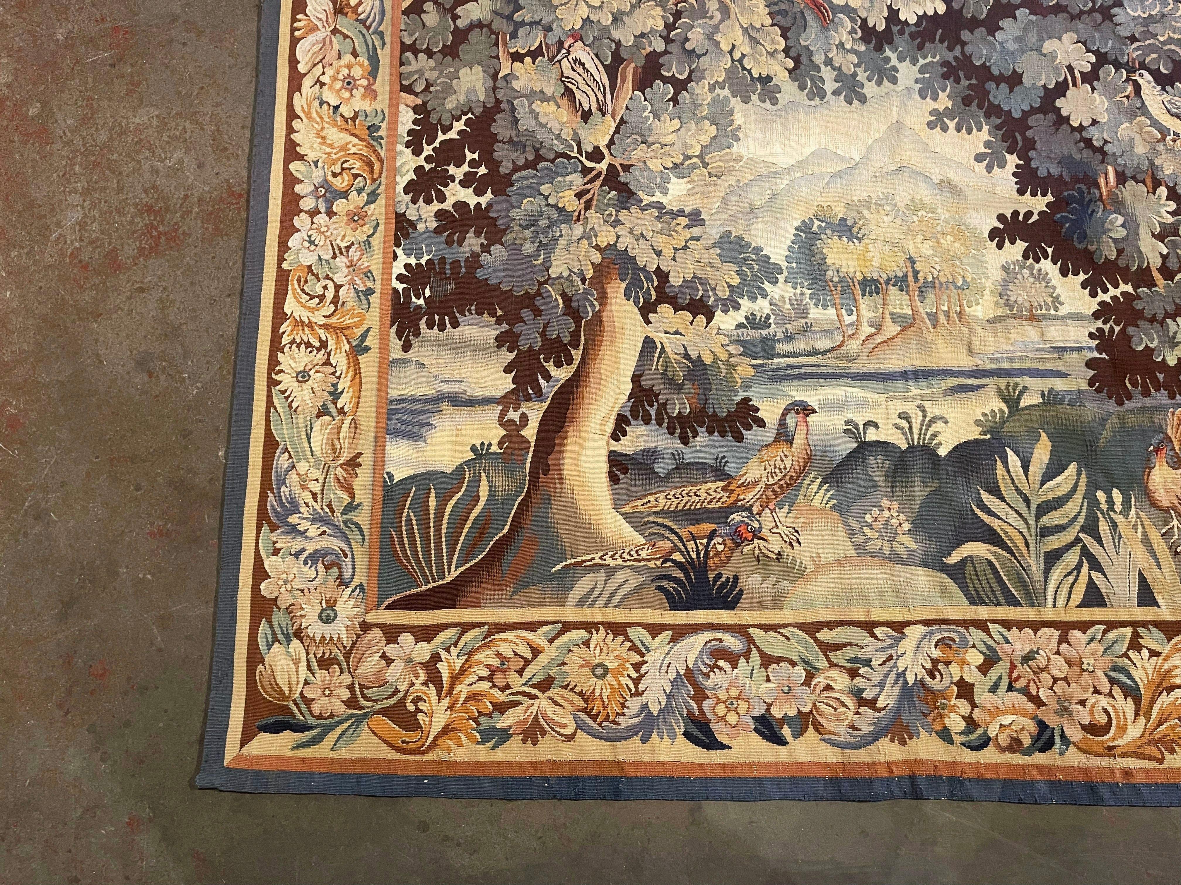 Decorate a wall or a staircase with this elegant and colorful antique tapestry. Handwoven in Aubusson, France circa 1880, the rectangular wall decor composition, depicts a landscape scenery with large trees and birds in the foreground, and a pond in