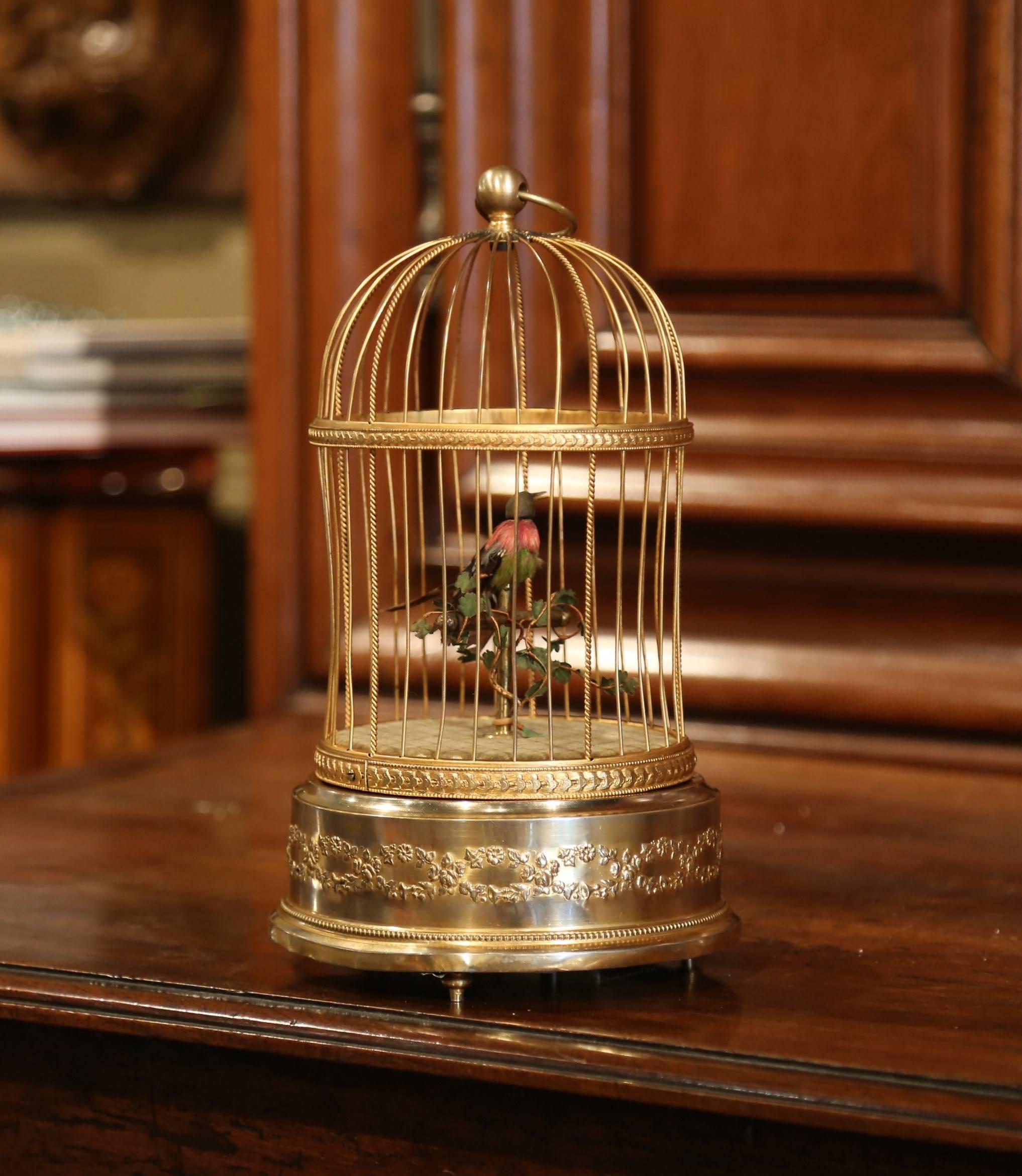 This antique birdcage was found in Paris; crafted circa 1890, the cage is rounded in shape with a dome. Inside it, a miniature automaton feathered colorful bird sits on a branch and sings while moving his head, beak and tail when you activate the