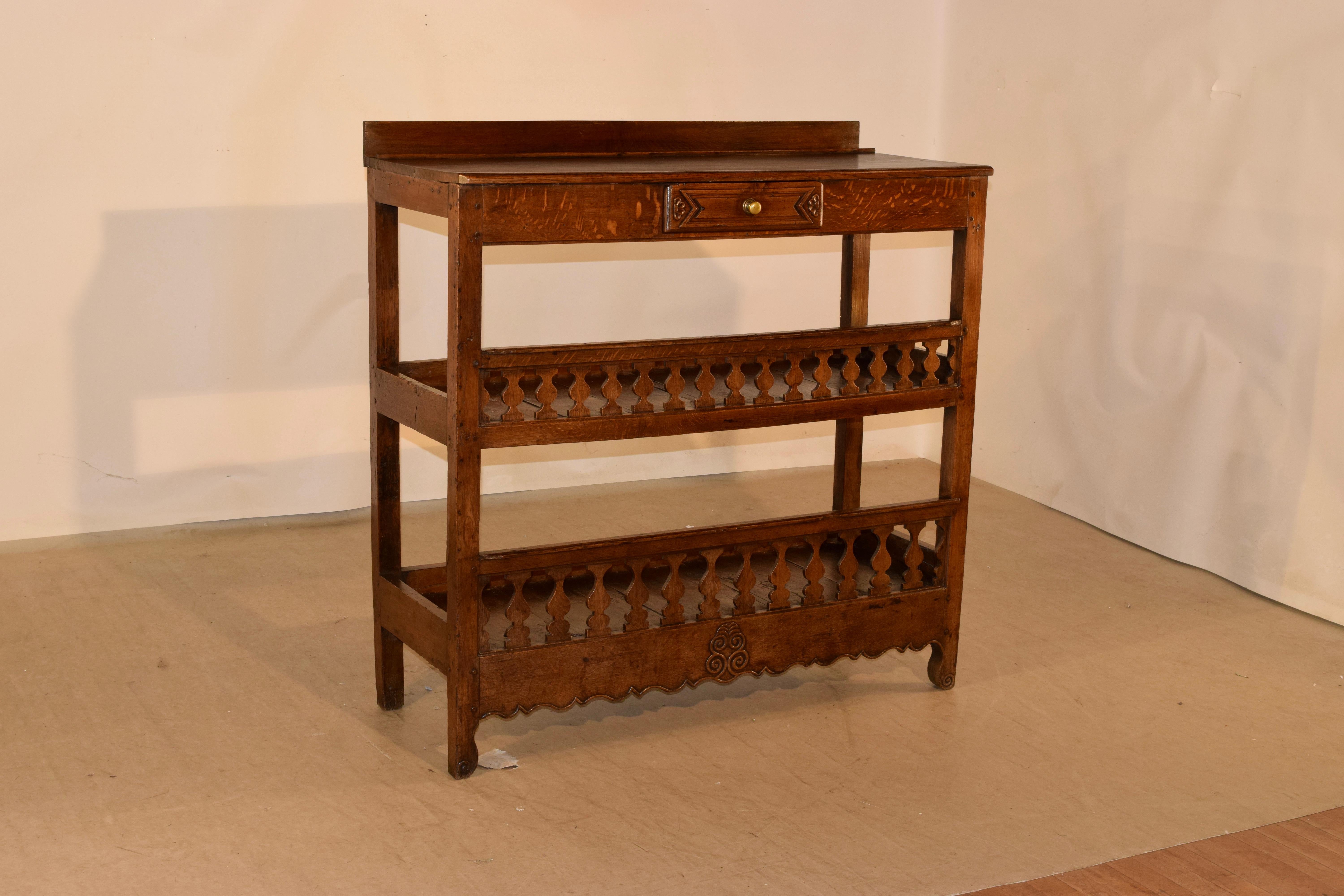 19th century oak baker's rack from France. This is a lovely form with a small backsplash following down to a simple apron which contains a single drawer. There are two shelves with galleries around each side and lovely hand carved baluster-type