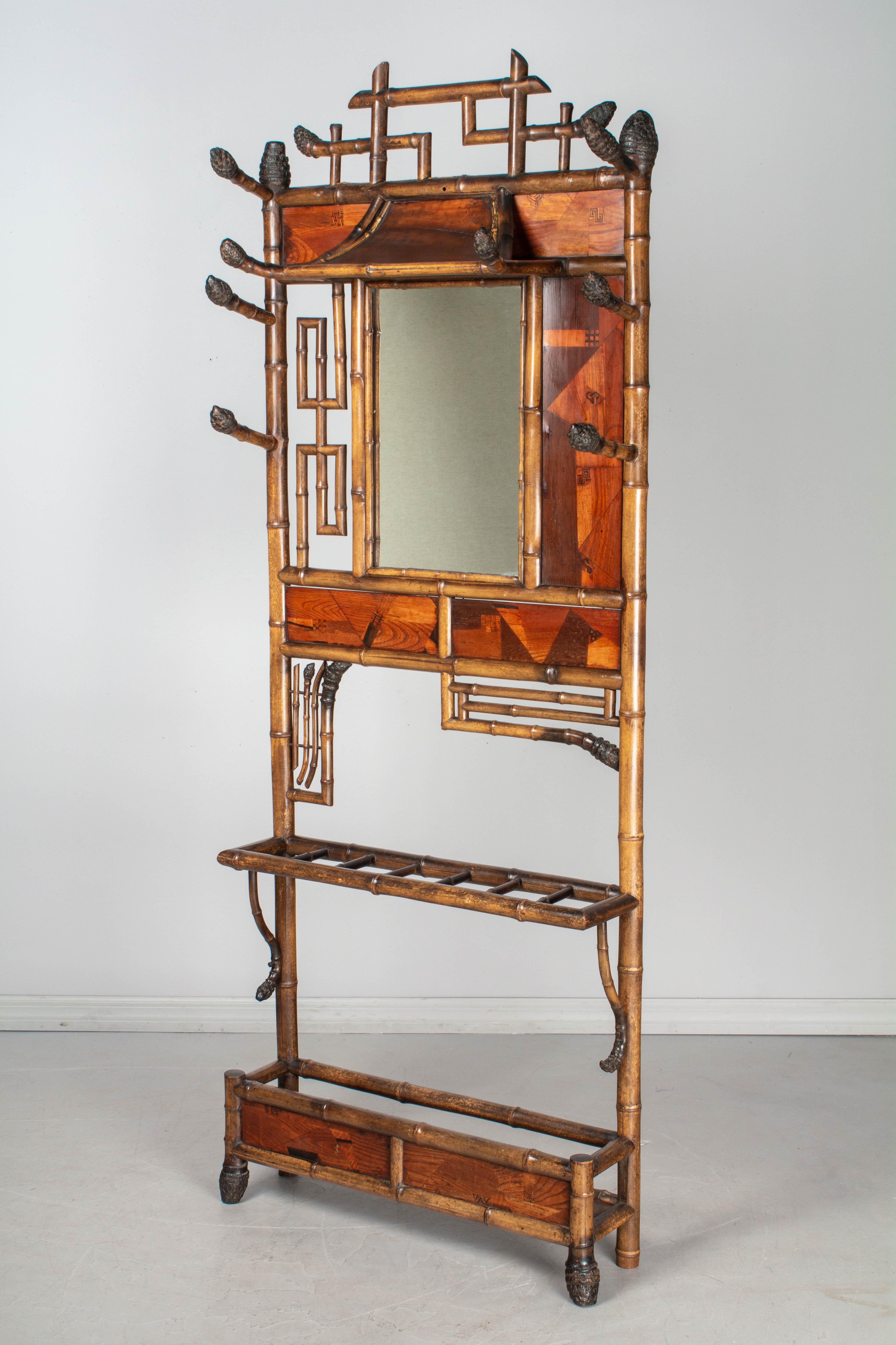 A 19th century French bamboo hall tree, or coat rack, of exceptional design, with asymmetric openwork bamboo sections, marquetry panels and an unusual pagoda style roof above the mirror. Exquisite Japanese marquetry panels with a patchwork of