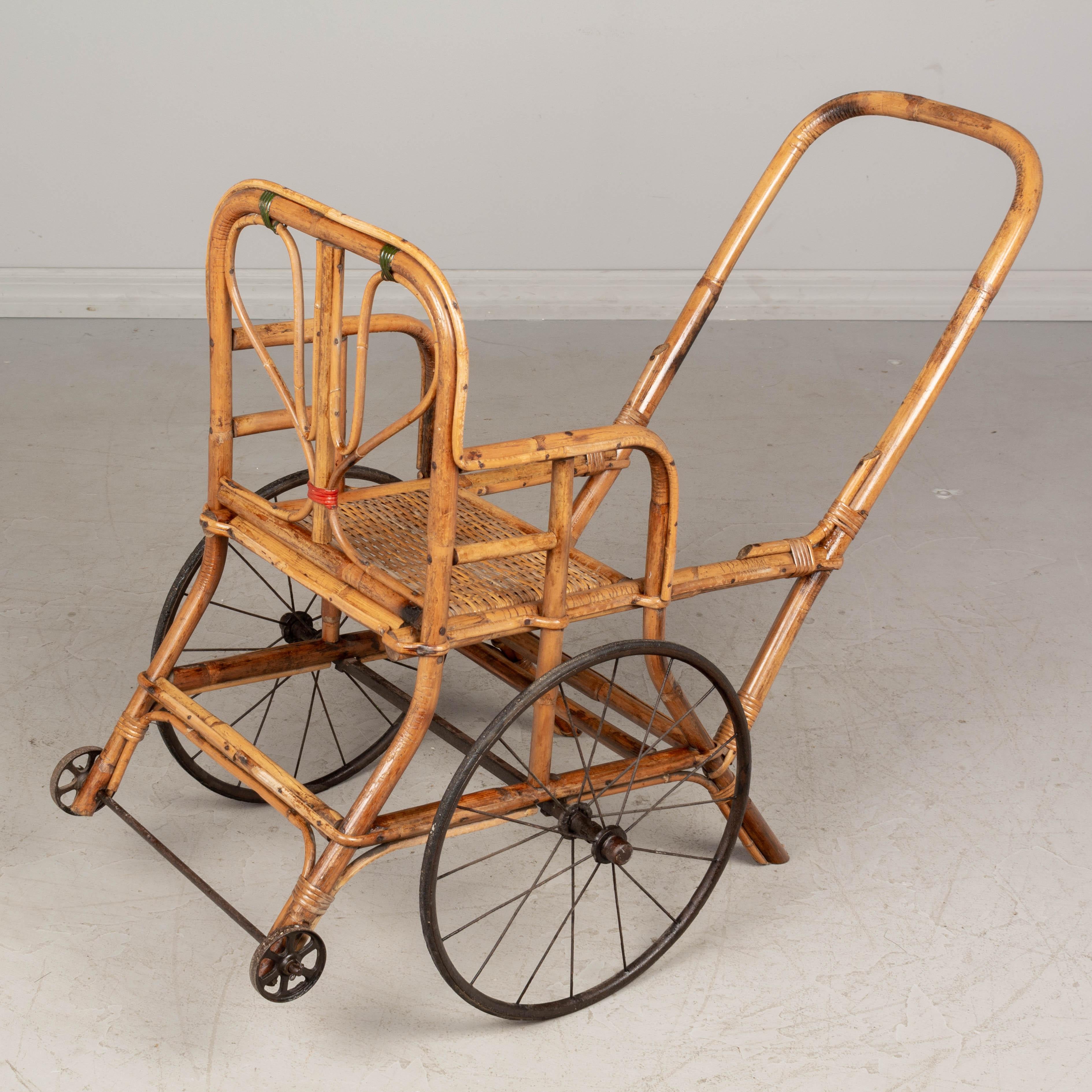 A 19th Century French pousette, or baby stroller with a sturdy bamboo frame and woven rattan seat. Beautifully crafted with touches of green and red binding for decoration. Very good condition for the age, this carriage rolls smoothly. The wheels