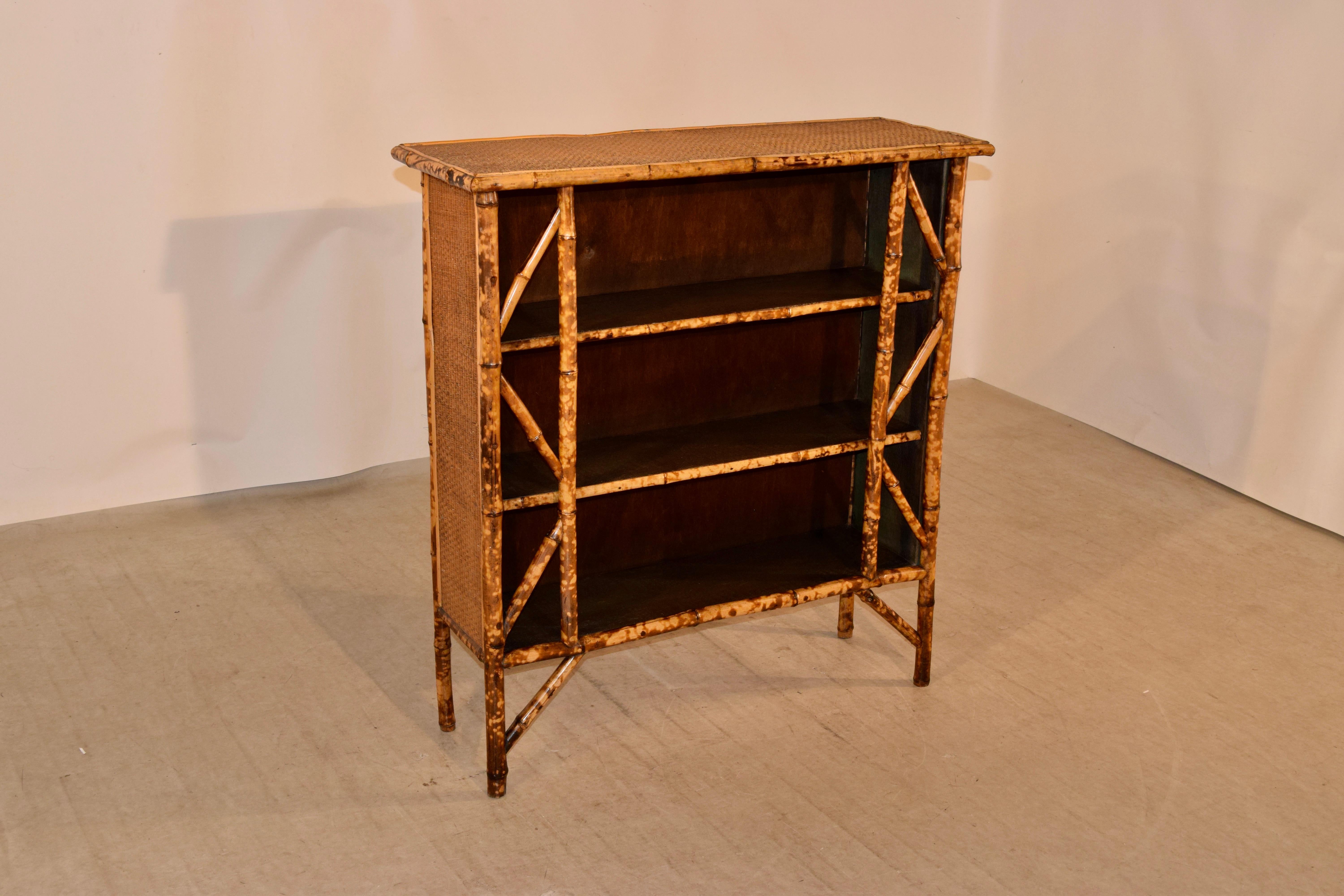 19th century bamboo shelf from France made from tortoise bamboo and pine. The top and sides are covered in rush and the case contains three shelves, all covered in alligator grained wallpaper, which has been painted. The piece has a nice patterned