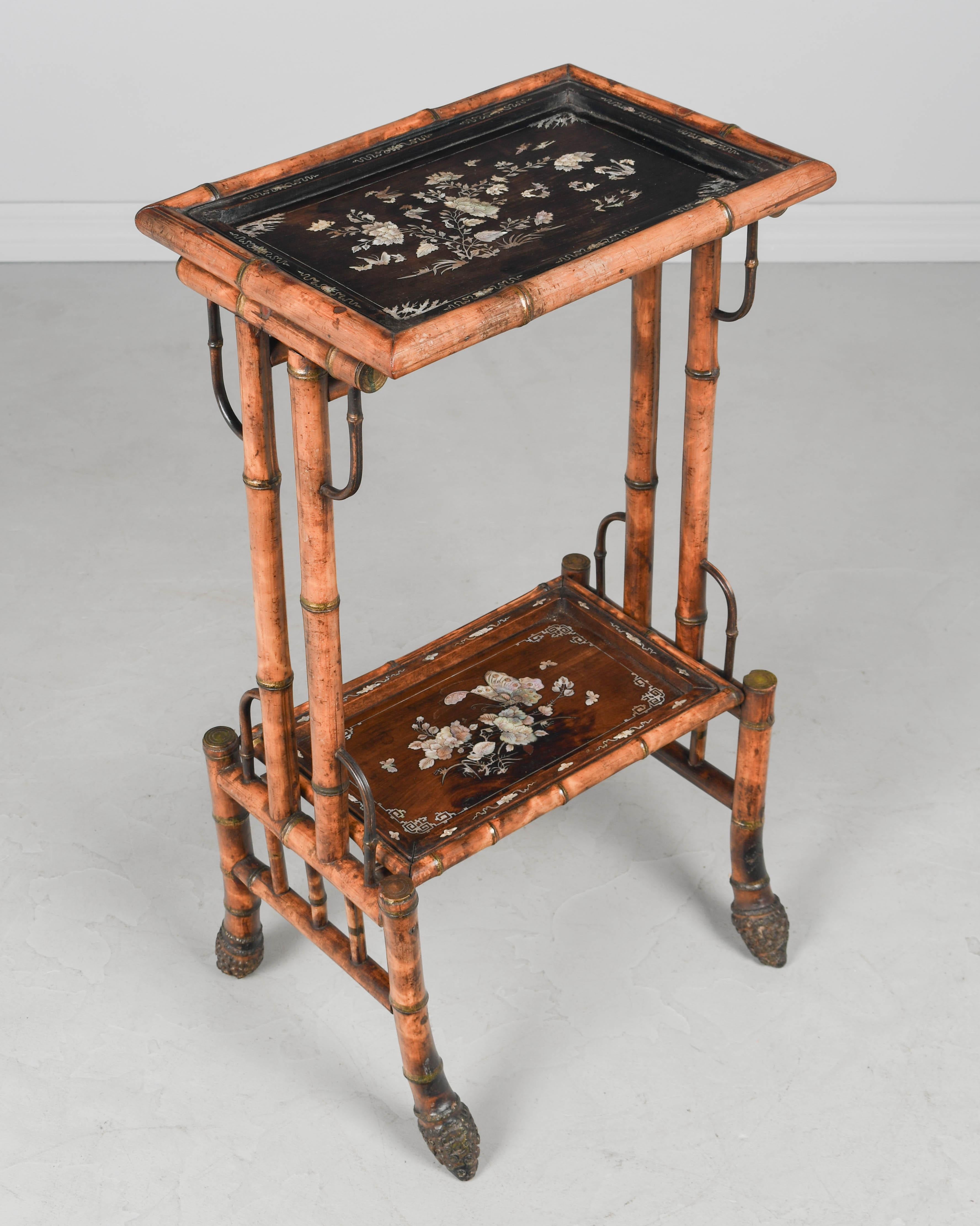 Tavolino Aesthetic Movement francese del XIX secolo con struttura in bambù e piano in palissandro intarsiato in madreperla e ripiano inferiore. Intarsio iridescente e luminoso di fiori e farfalle con bordo decorativo. Circa 1870-1890. 
Dimensioni: