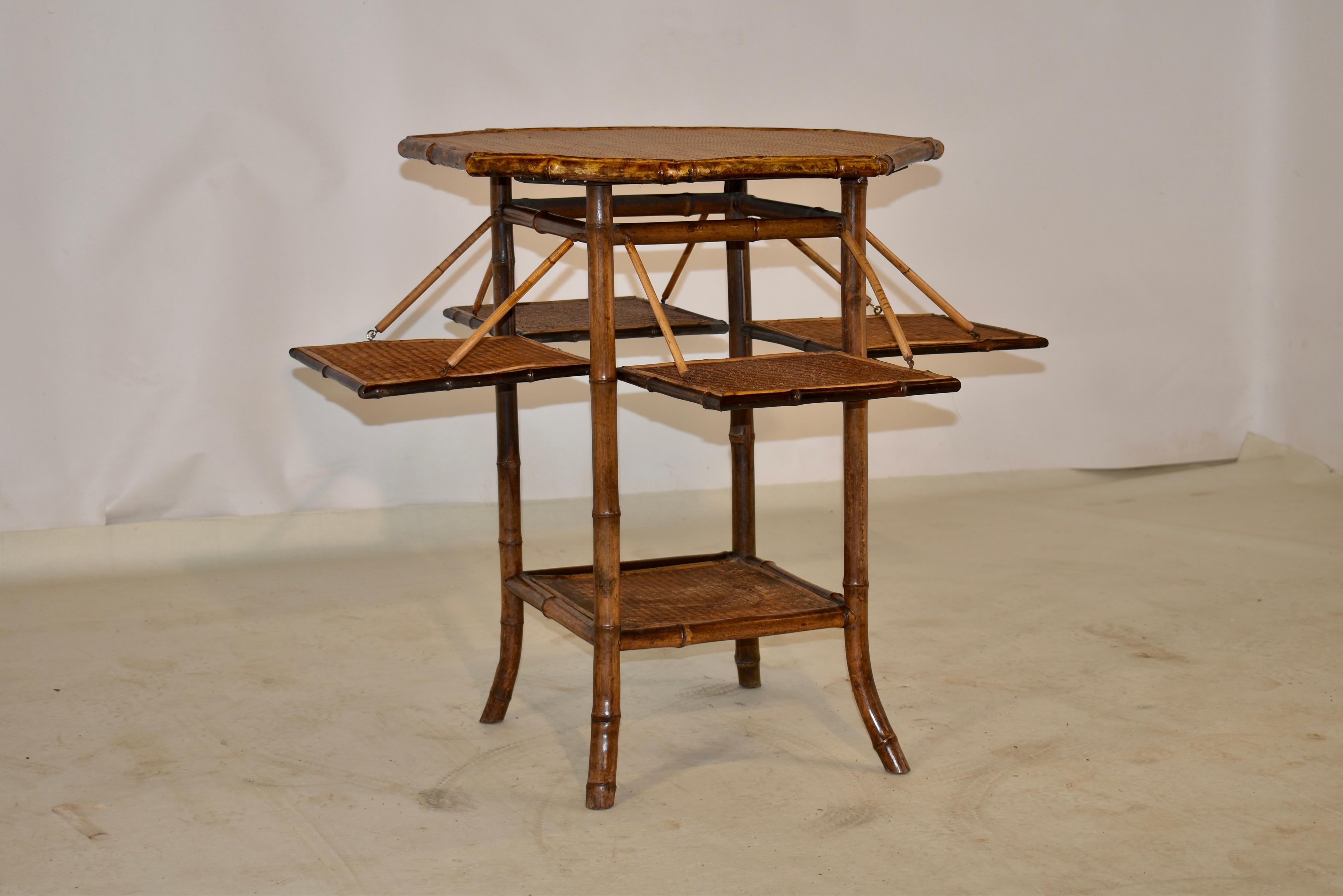 19th century bamboo table from France with rush covered top and shelves. The top is octagonal shaped and follows down to four mobile shelves, which open and close for easy storage, over splayed legs, joined by a lower shelf, which is also covered