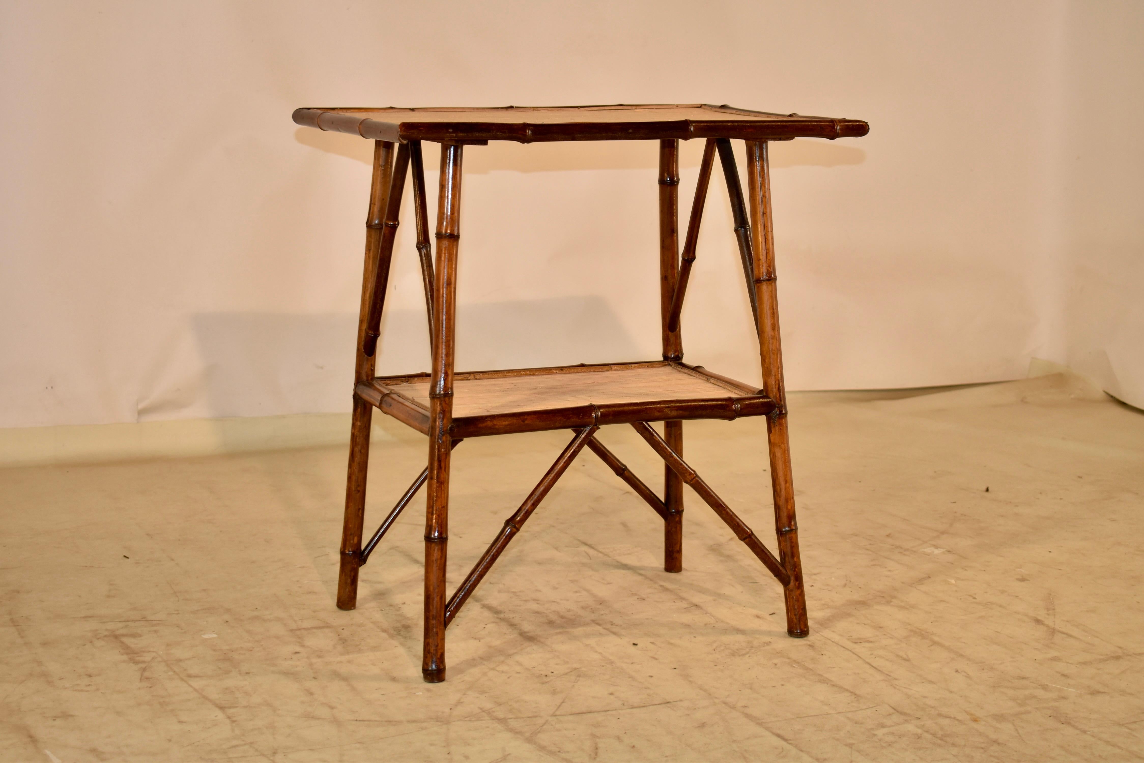 19th century bamboo side table from France.  The top of the table has edges banded in bamboo trim, and is supported on splayed bamboo legs, joint by a lower shelf, also trimmed with bamboo trim.  Both the top and lower shelves are covered in