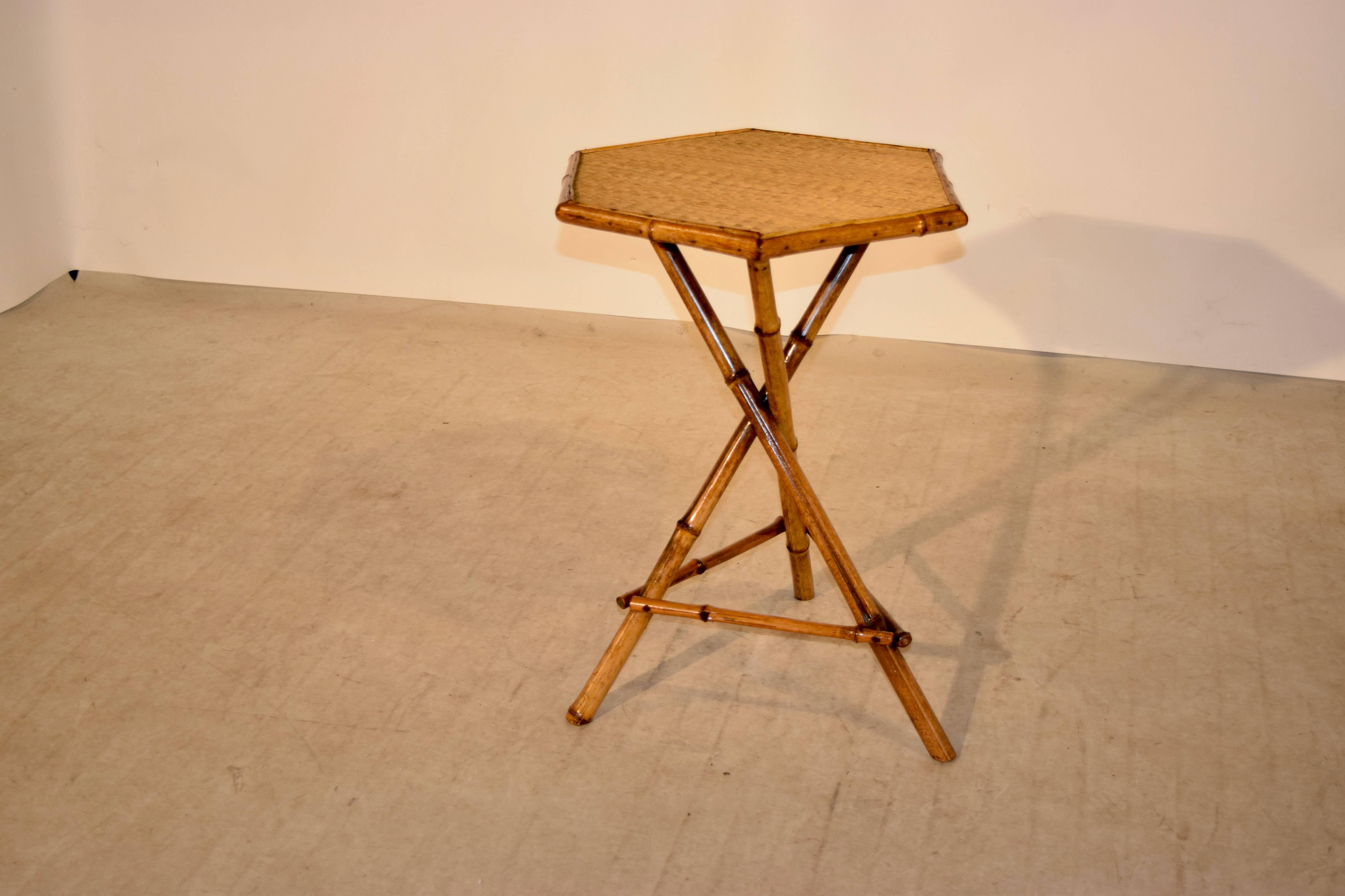 19th century bamboo side table from France. The top has six sides and is covered with rush and has a base which is made up of three crossed legs, joined by crossed stretchers.