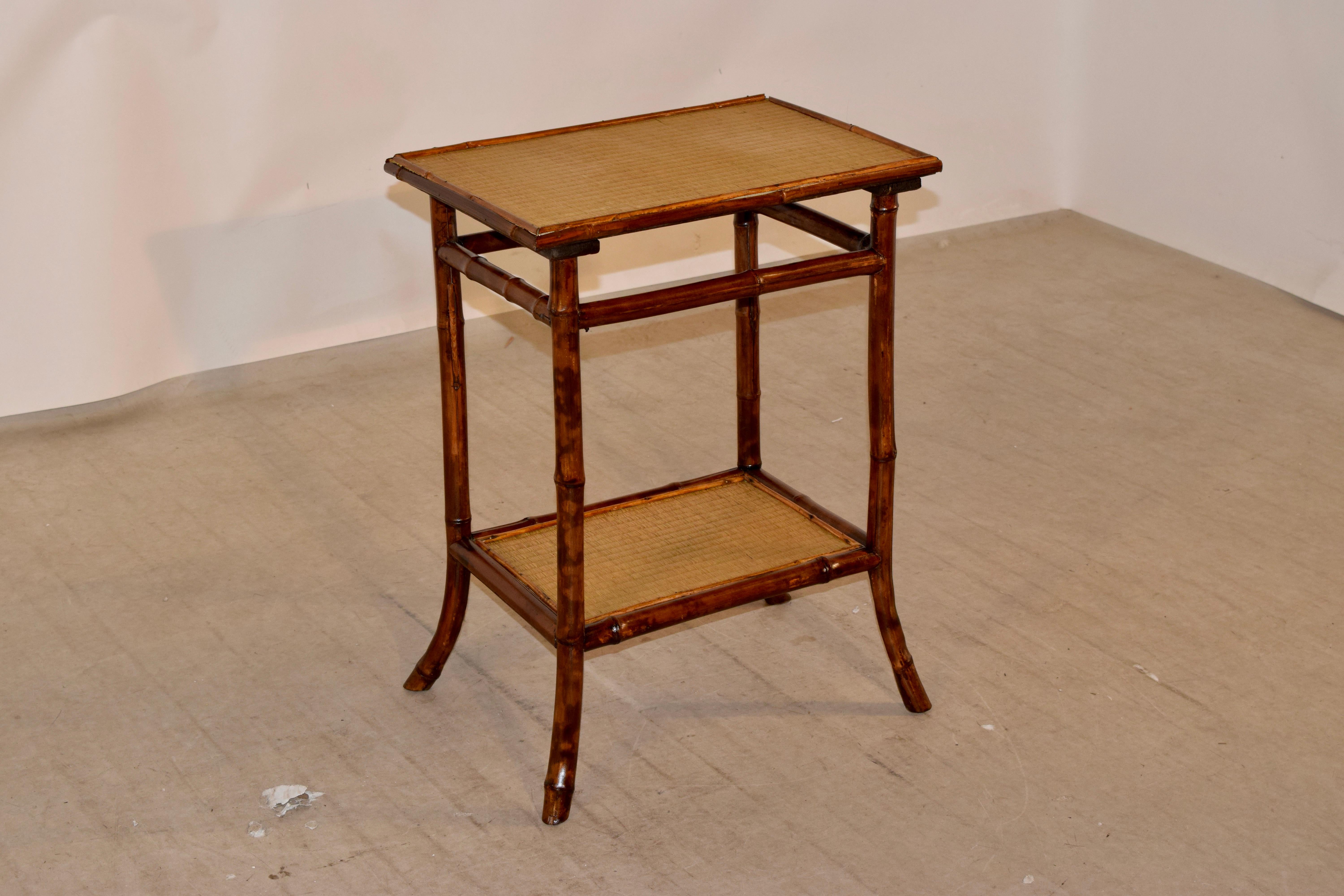 19th century French bamboo table with rush covered top and lower shelf. The top has an applied molding and follows down to stretchers, over a lower shelf, also with applied molding. Lovely splayed legs.