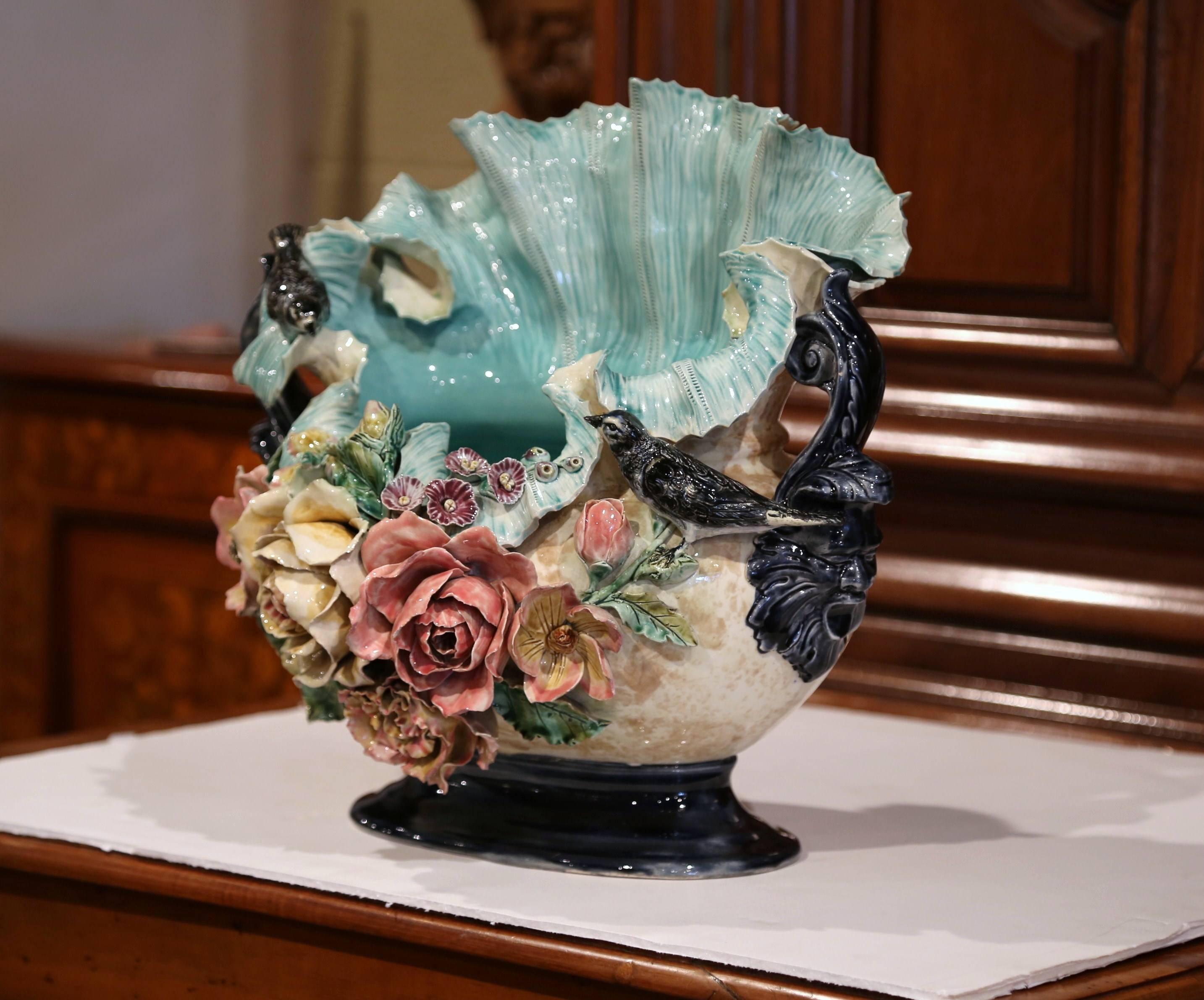 This large, unusual antique Majolica planter was crafted in France, circa 1860. The decorative porcelain cache pot is heavily decorated with colorful, high relief flowers, green leaves and is further embellished with a pair of birds and intricate