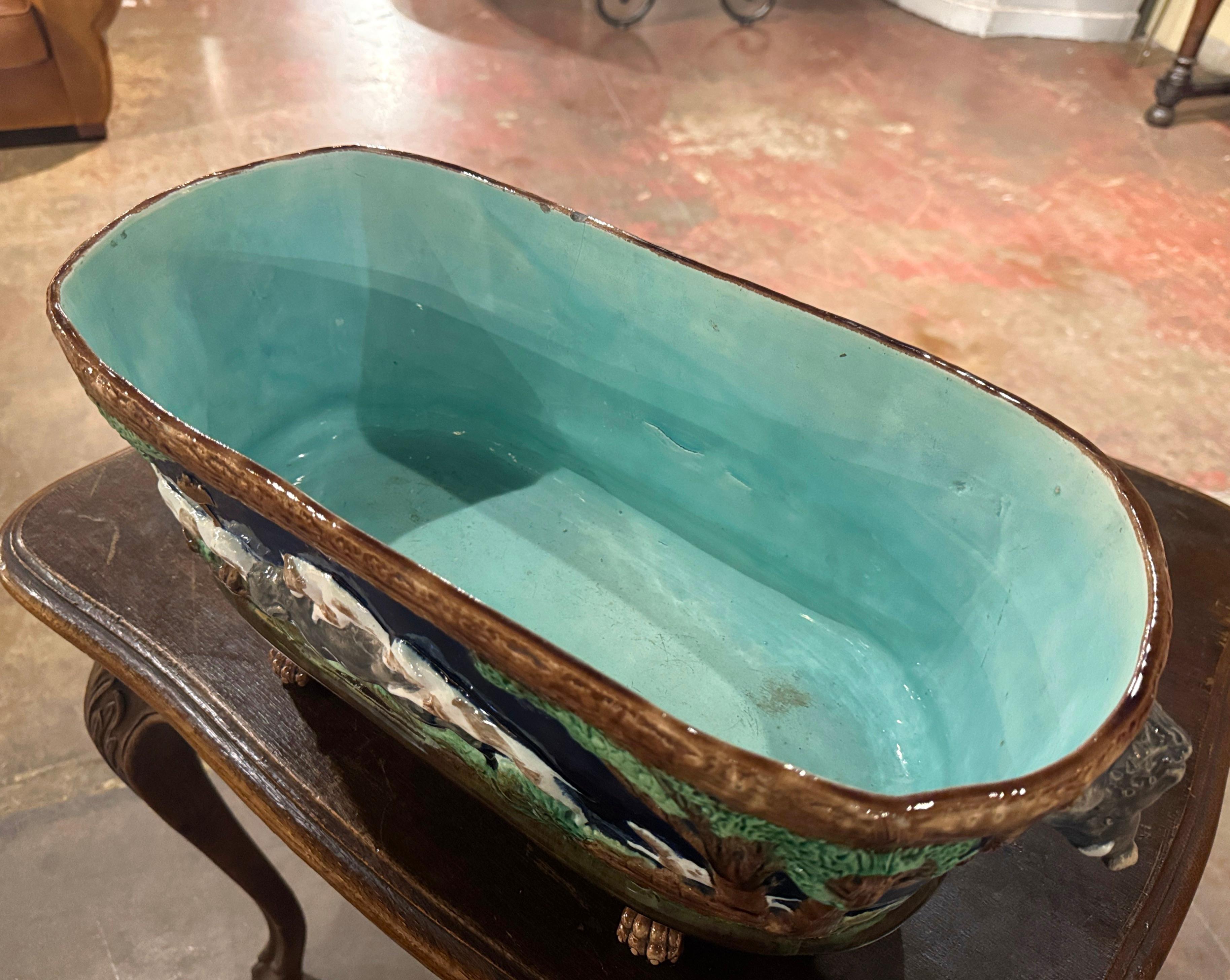 Decora un capanno di caccia o un ranch con questa colorata fioriera antica. Realizzata a Sarreguemines, in Francia, intorno al 1880, l'elegante fioriera in maiolica poggia su piedi a zampa ed è dotata di manici a testa di cinghiale. Il cache pot