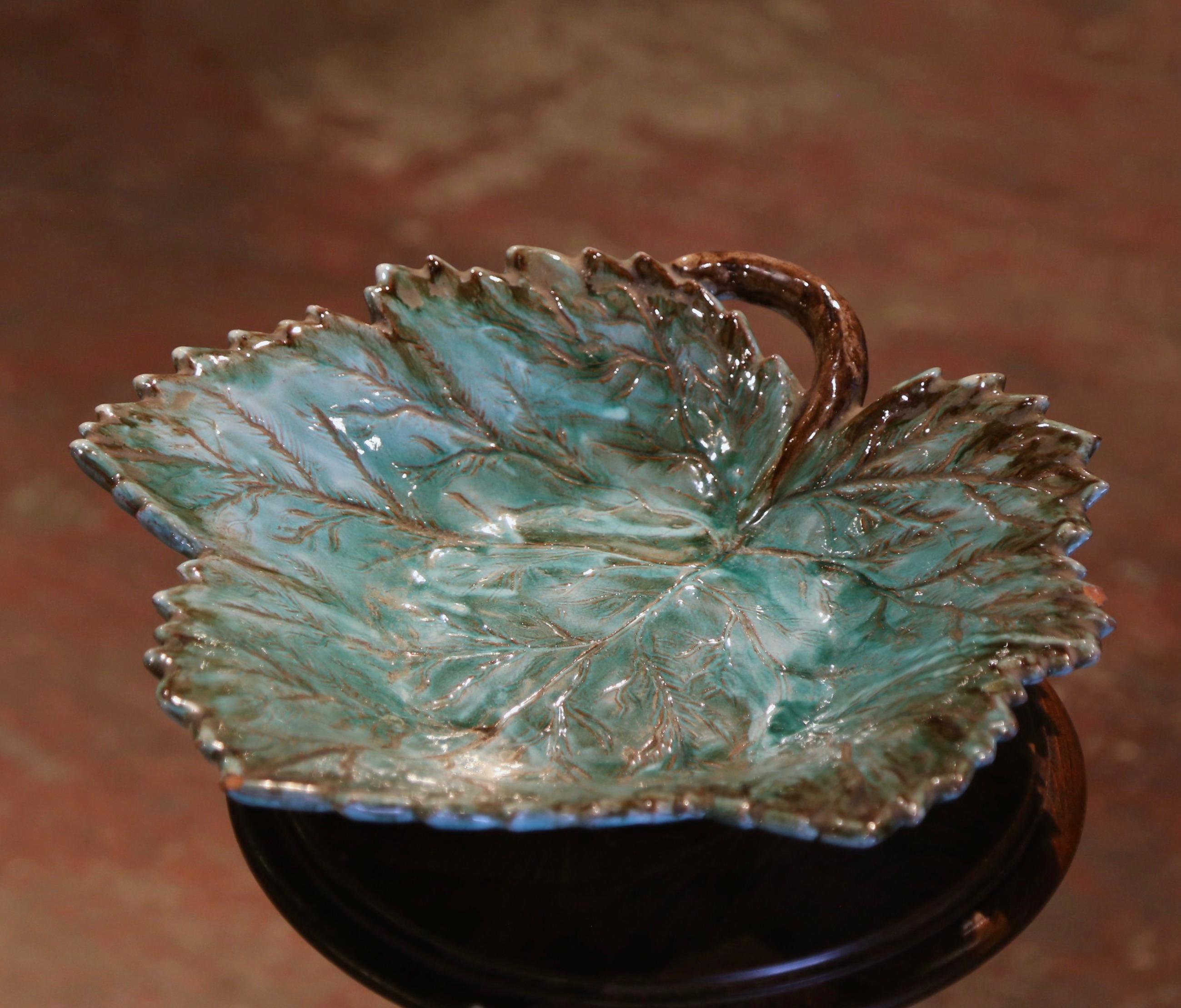 Decorate a table or shelf with this colorful antique platter. Crafted in France circa 1880, the large tray features a hand painted leaf-form dressed with a branch form handle both in high relief. The elegant ceramic dish is in excellent condition