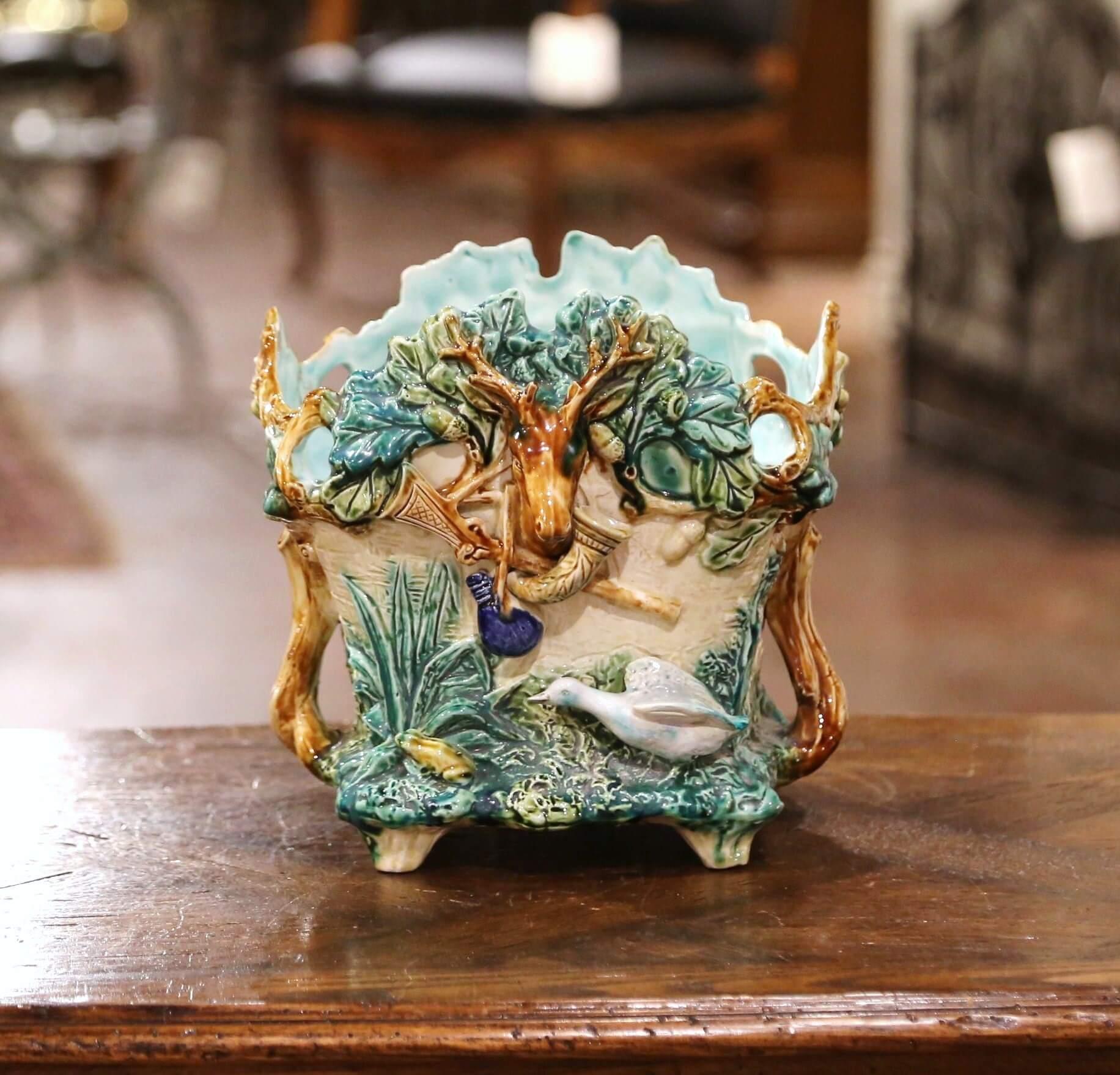 Decorate a ranch or hunting lodge with this colorful majolica jardinière. Created in France by L'Hermine a Orchies, circa 1880, and almost square in shape, the antique porcelain cache pot features exquisitely rendered hunting motifs on all four