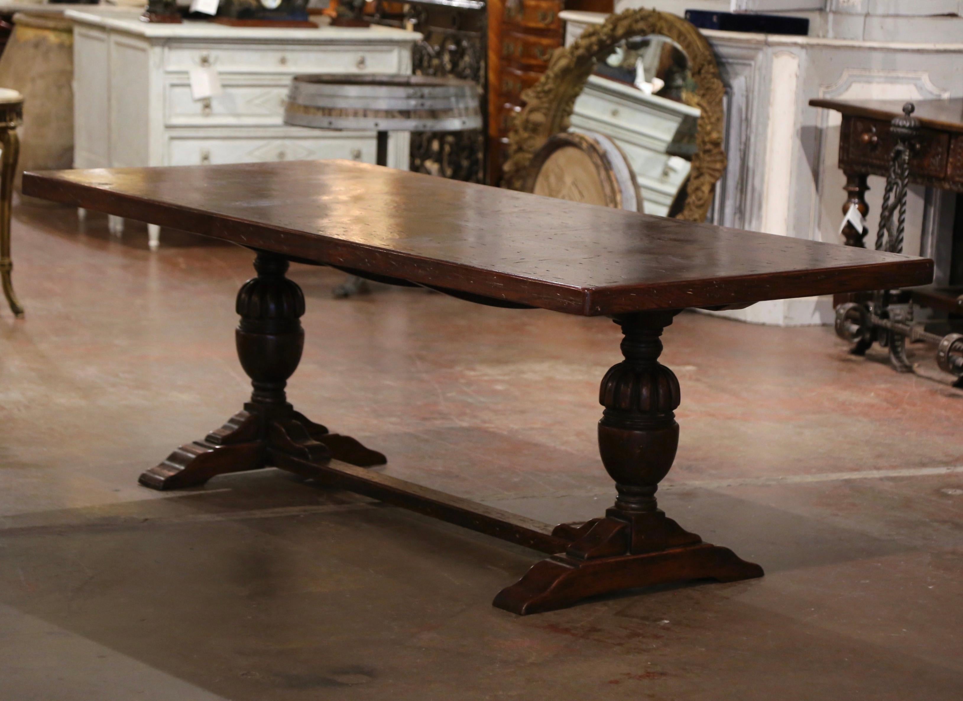  Cette grande table de salle à manger ancienne a été fabriquée dans le nord de la France vers 1870. Construite en chêne, la table repose sur une base à tréteaux, soutenue par des pieds balustres sculptés à la main et reliés à la base par un épais