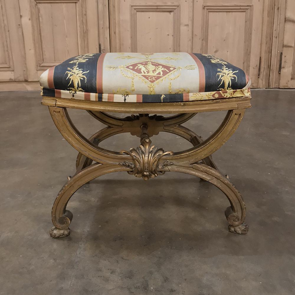 19th century French Louis XVI giltwood stool features a design that dates back to ancient Greece, and the original gilt finish accentuates the hand-carved embellishments of the wooden frame. Upholstery is in excellent condition in Neoclassical style