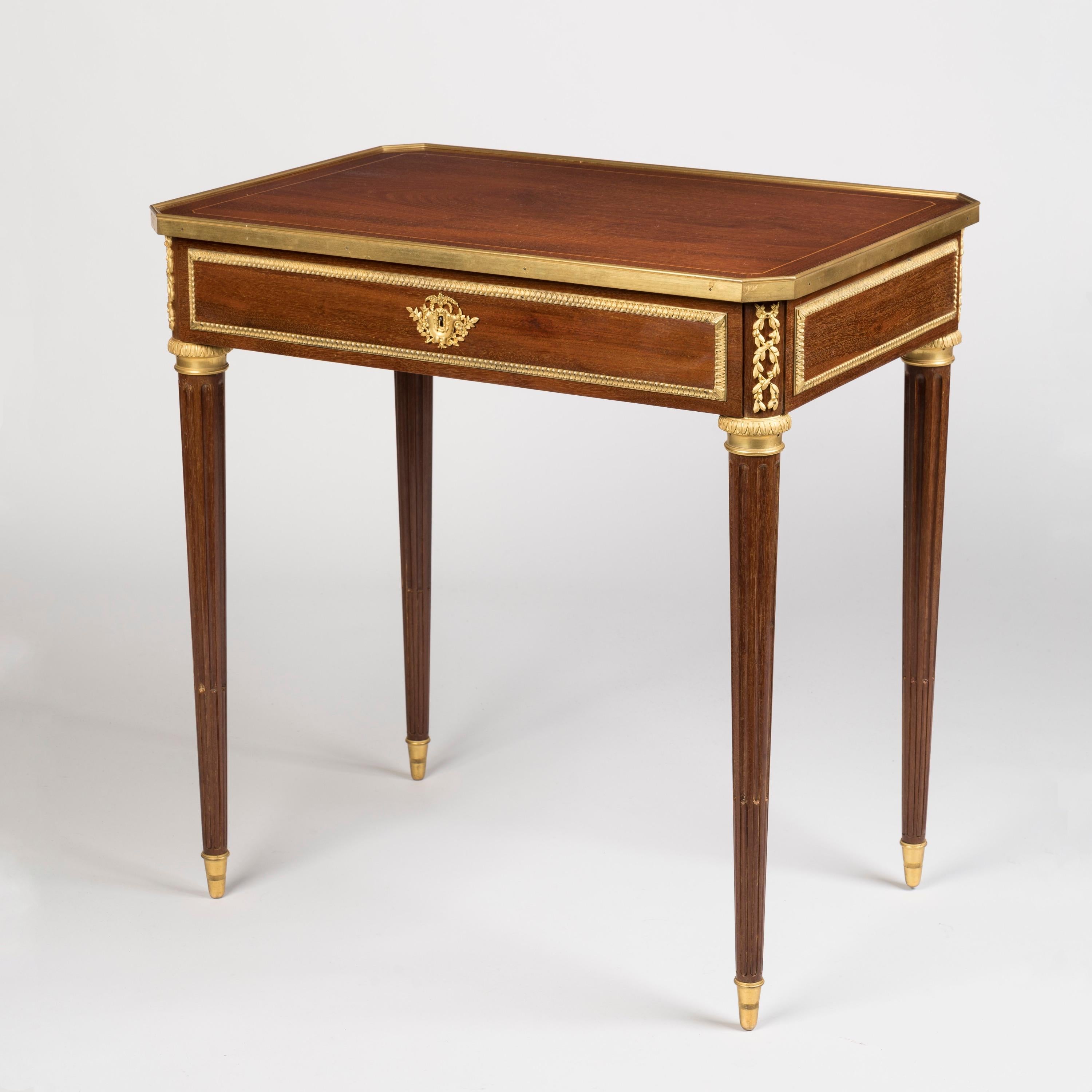 A Louis XVI style writing table
By Lexcellent of Paris

Of restrained elegance and sumptuous finish with gilt bronze mounts, the mahogany-veneered writing table supported on tapering stop-fluted legs with bronze sabots and capitals, the writing