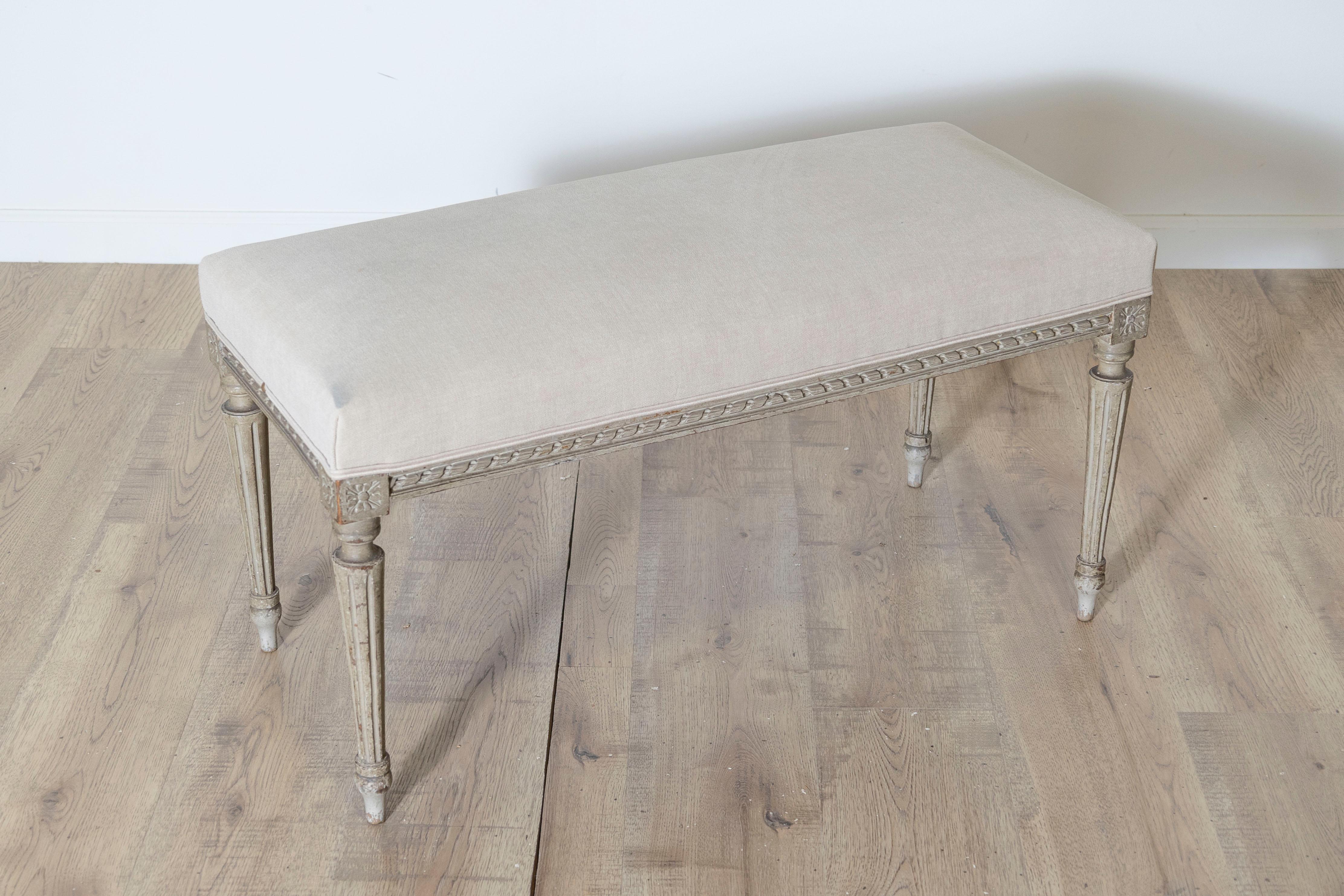 Magnifique banc de style Louis XVI français du XIXe siècle, vers 1800, fabriqué en bois et peint dans d'élégantes nuances de gris-vert. Le banc repose gracieusement sur quatre pieds cannelés, une caractéristique du design-Light-Light, ajoutant une